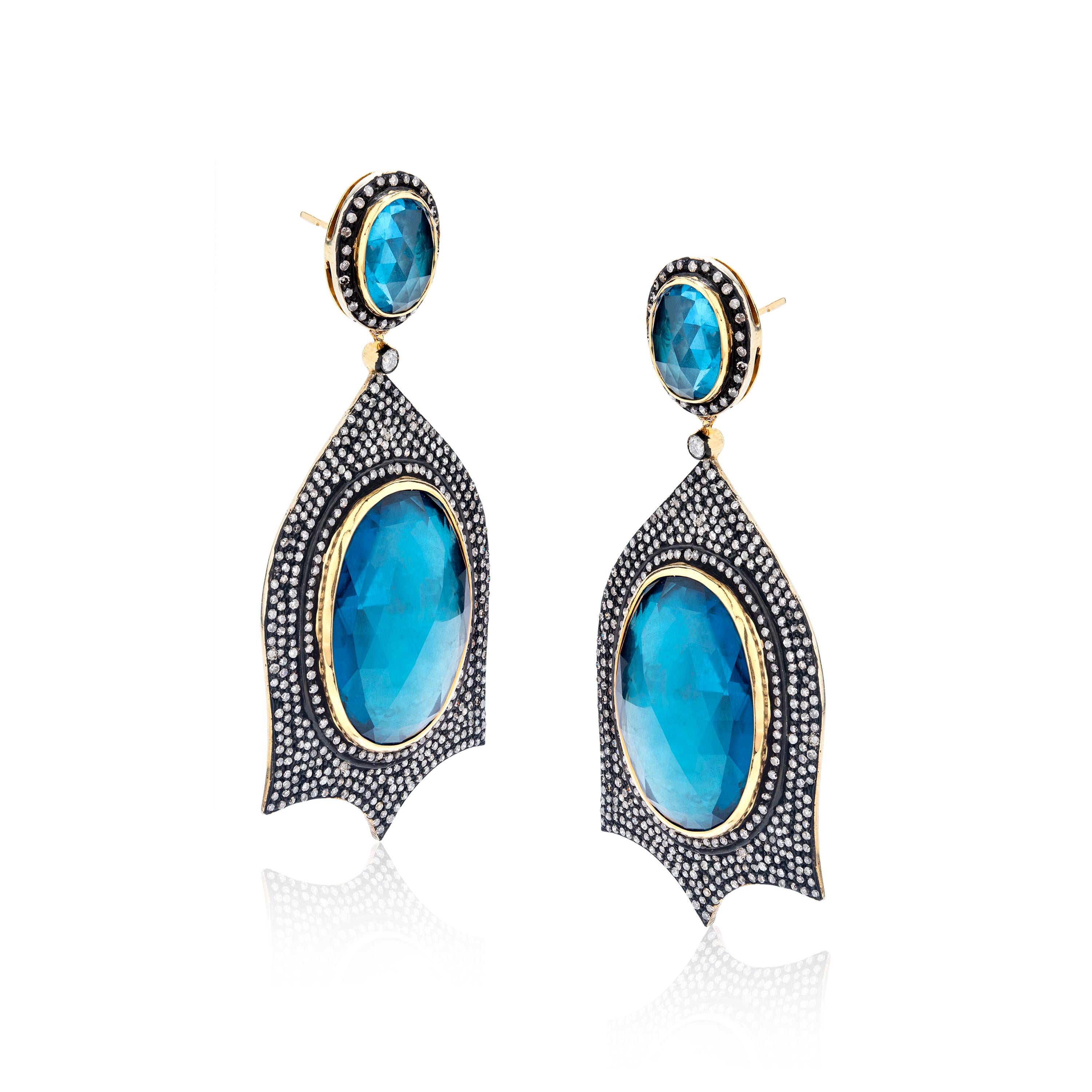 This Gemistry, plush pair of Blue Topaz and Diamond Victorian earrings is mounted on 18K/925 Sterling Silver and Yellow & Black Rhodium. The dangle earpieces are well decorated with diamonds, weighing 8.4 Cts. The diamonds are l in clarity and HI,