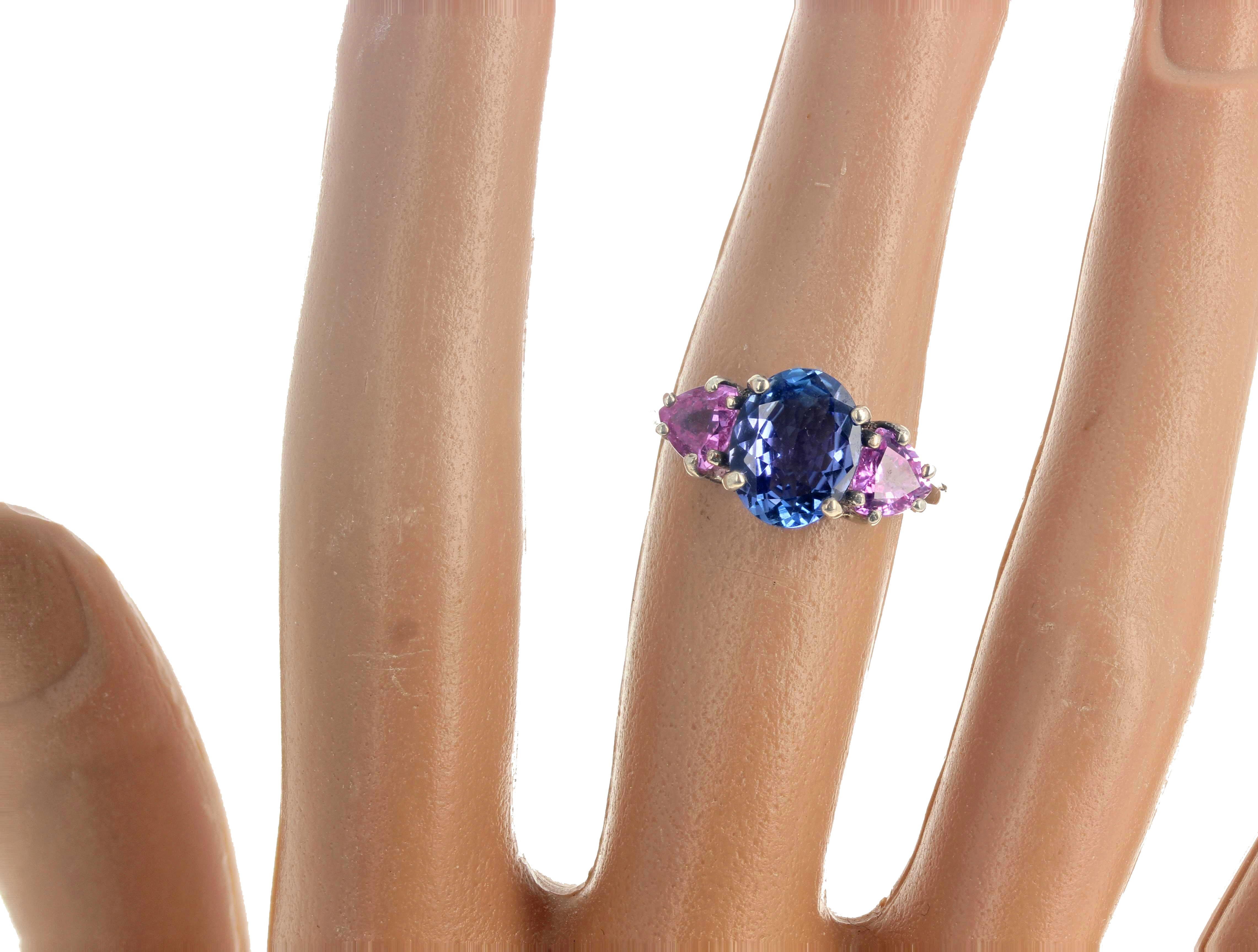 This petite brilliant blue natural 2.15 carat Tanzanite (10 mm x 8 mm) center gemstone is flanked by two natural sparkling intense pink Sapphires ( 5.5mm x 5.5mm - 0.45 carats each approximately).  Set in sterling silver this ring is size 7