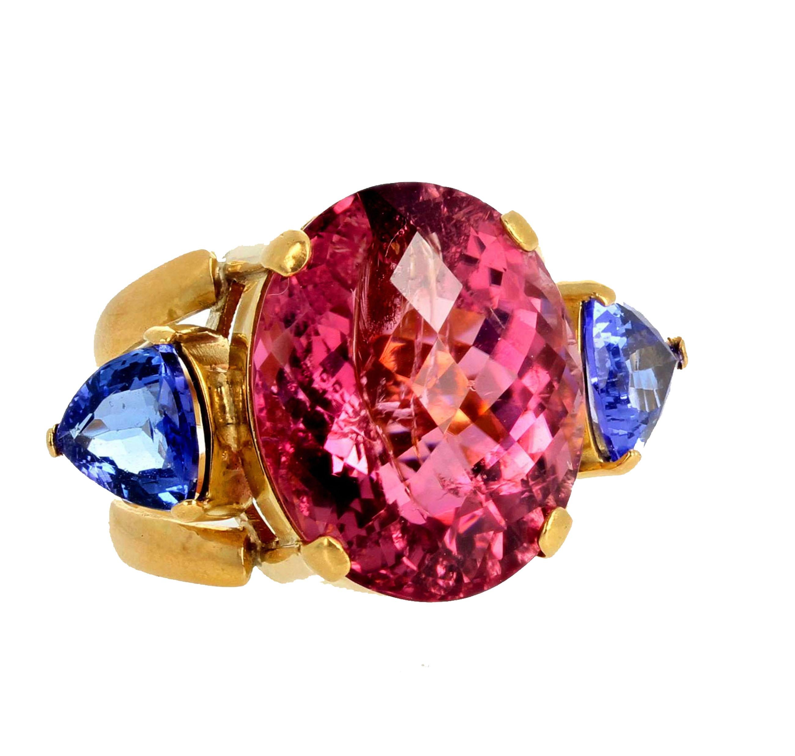 This extraordinary ring is a glittering intense pink checkerboard gemcut natural brilliant Tourmaline enhanced with 1 Ct each of natural Tanzanite trillions set in this 18Kt yellow gold ring size 7 (sizable).  This magnificent ring sits high on the