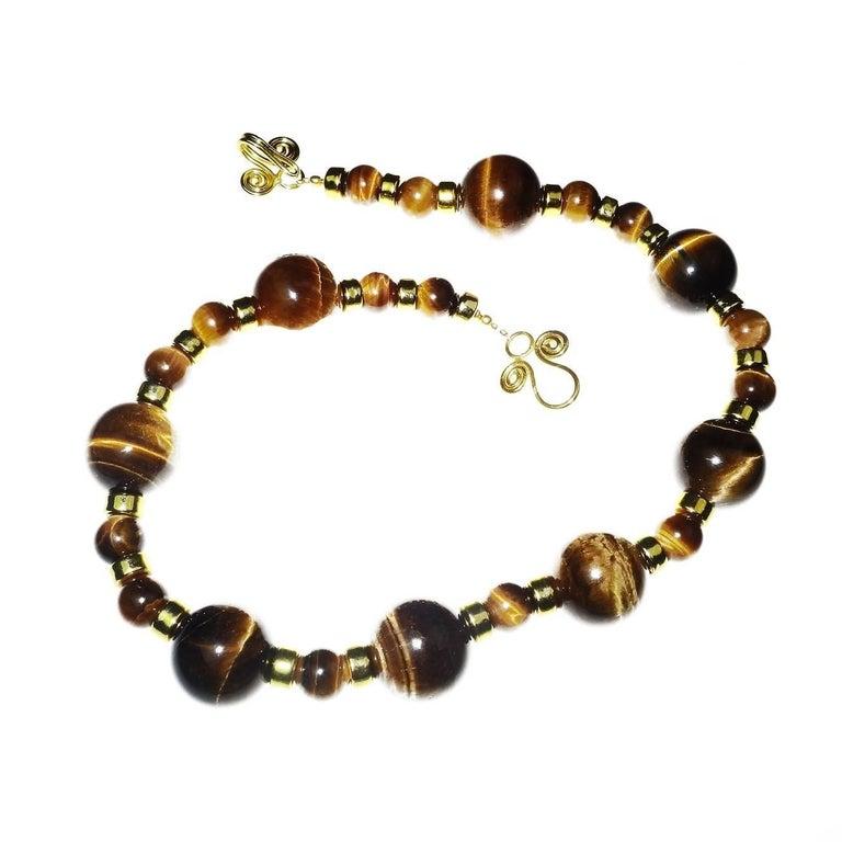 Princess length necklace of glowing, Chatoyant Tiger’s Eye in 10 MM and 20 MM with gold tone accents and swirly hook 18K gold overlay clasp. The entire length of the necklace is 17 inches. Remember that with this size necklace that when it is closed