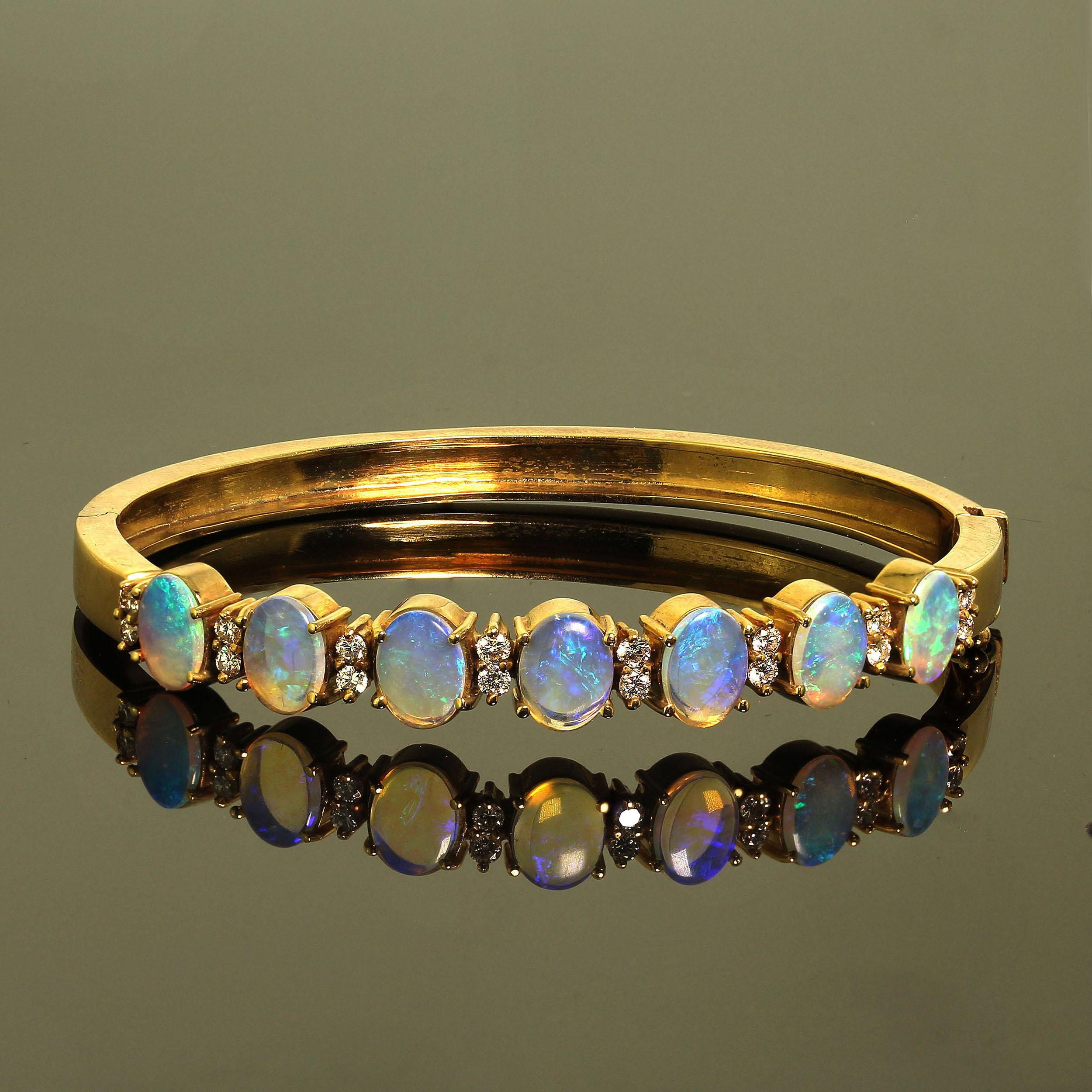 Glorious Opal and Diamond Bracelet set in 18K yellow gold.  This is a hand made bangle style bracelet with seven oval opals (8 X 6 MM)  across the front of the bracelet.  The opals are enhanced by 16 Diamonds of approximately 0.50 carats total