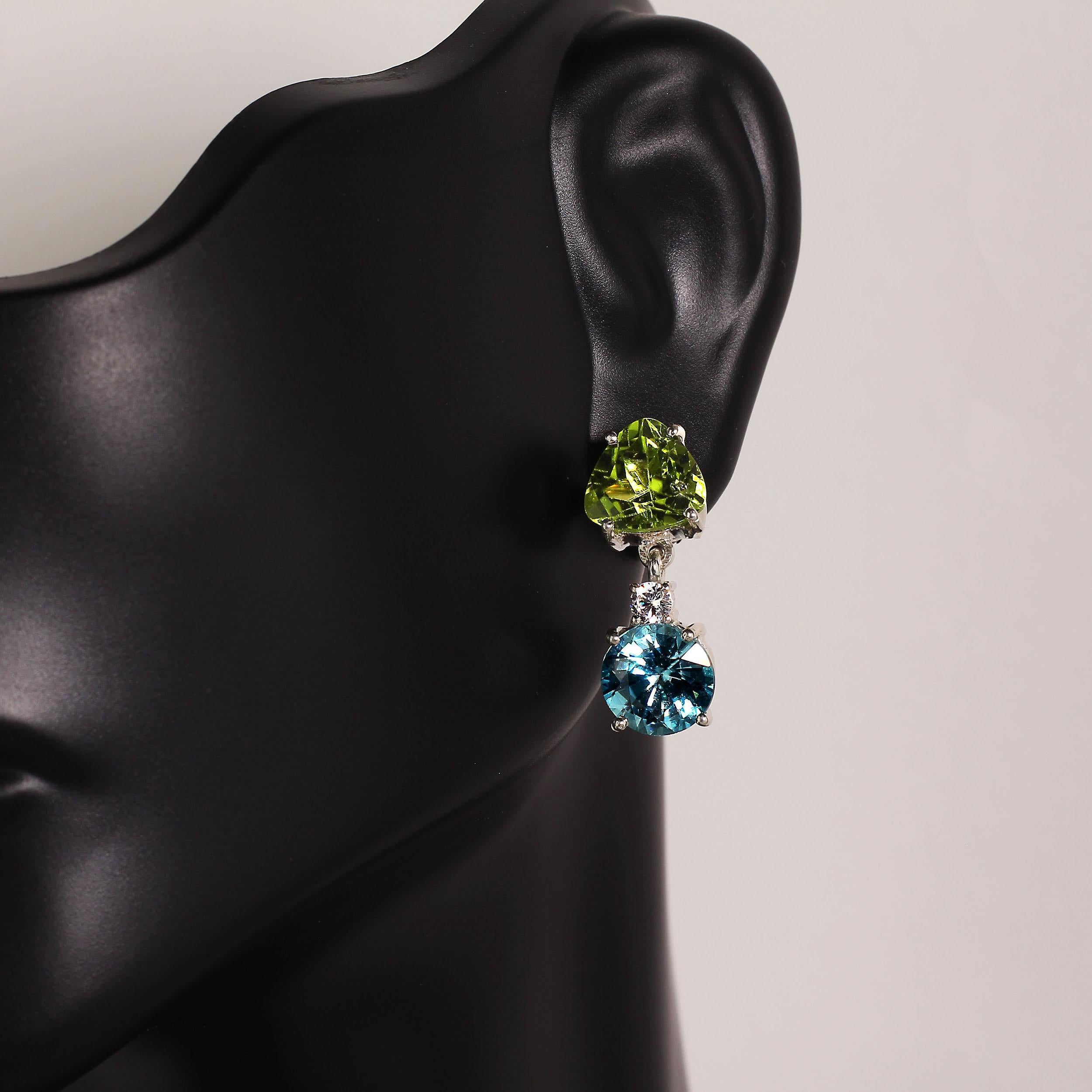 Lively green Peridot and blue Zircon dangle earrings. These swinging earrings feature a trillion sparkling Peridot, a white Cambodian Zircon, and a round bright blue Zircon. The hand made Sterling Silver setting hinges to create maximum swing and