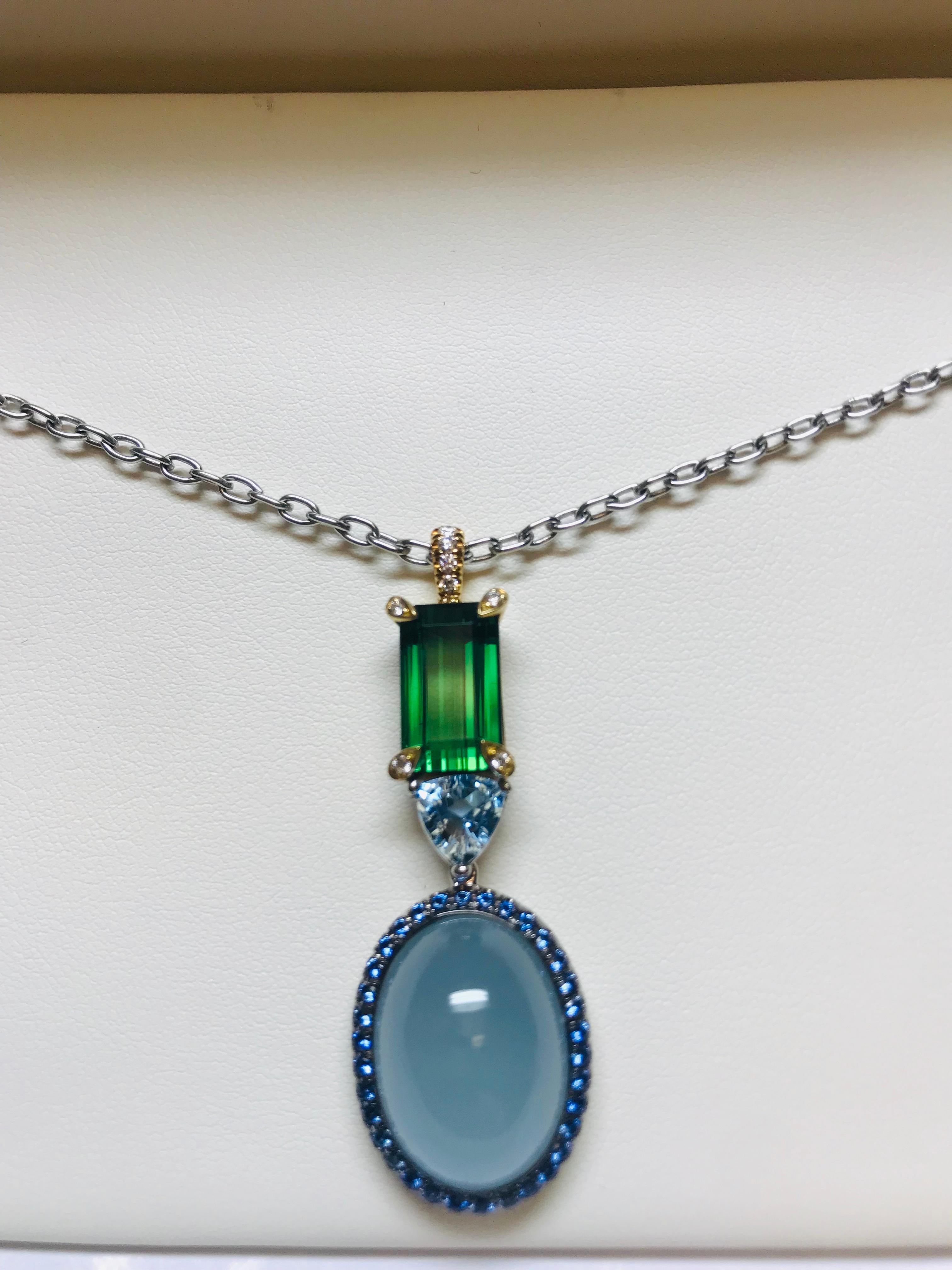 The incredible combination of colors in this pendant really make it stand out as a signature necklace. The oval cabochon cut Aquamarine surrounded by .61 carats of cornflower blue sapphires highlight the piece, with the 1.03 carat trillion cut