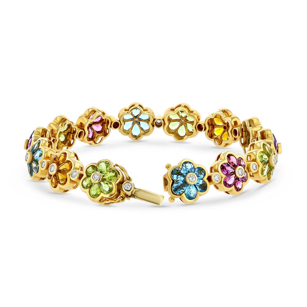 This vintage 18k yellow gold semi-precious gemstone and diamond bracelet is a vivacious homage to botanical divinity. In this bracelet vibrant gemstones come together with a bezel set diamond in the center to create an array of blue, orange, green,