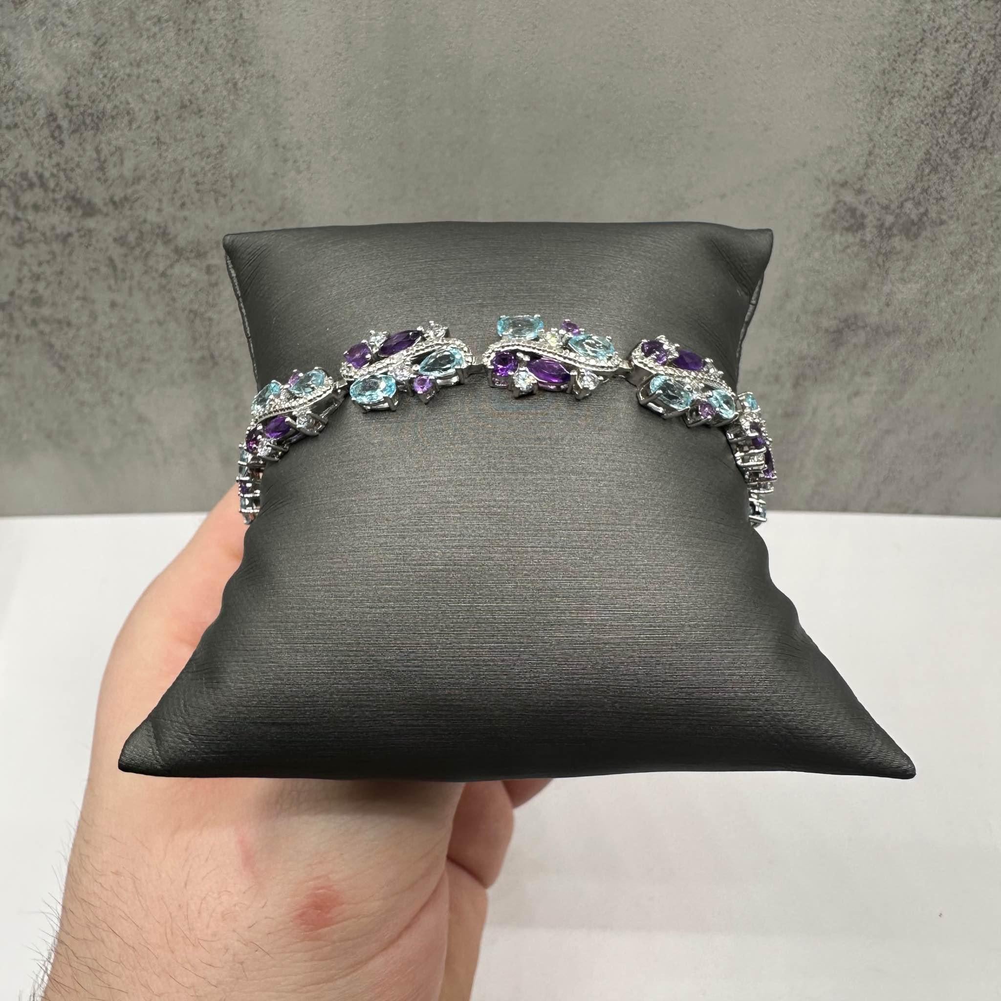 This stunning Gemstone Bracelet in sterling silver features 10ctw of natural amethyst, blue topaz, and white topaz, offering a beautiful blend of vibrant colors. The bracelet is 7 3/8 inches in length, making it a perfect fit for most wrists.
