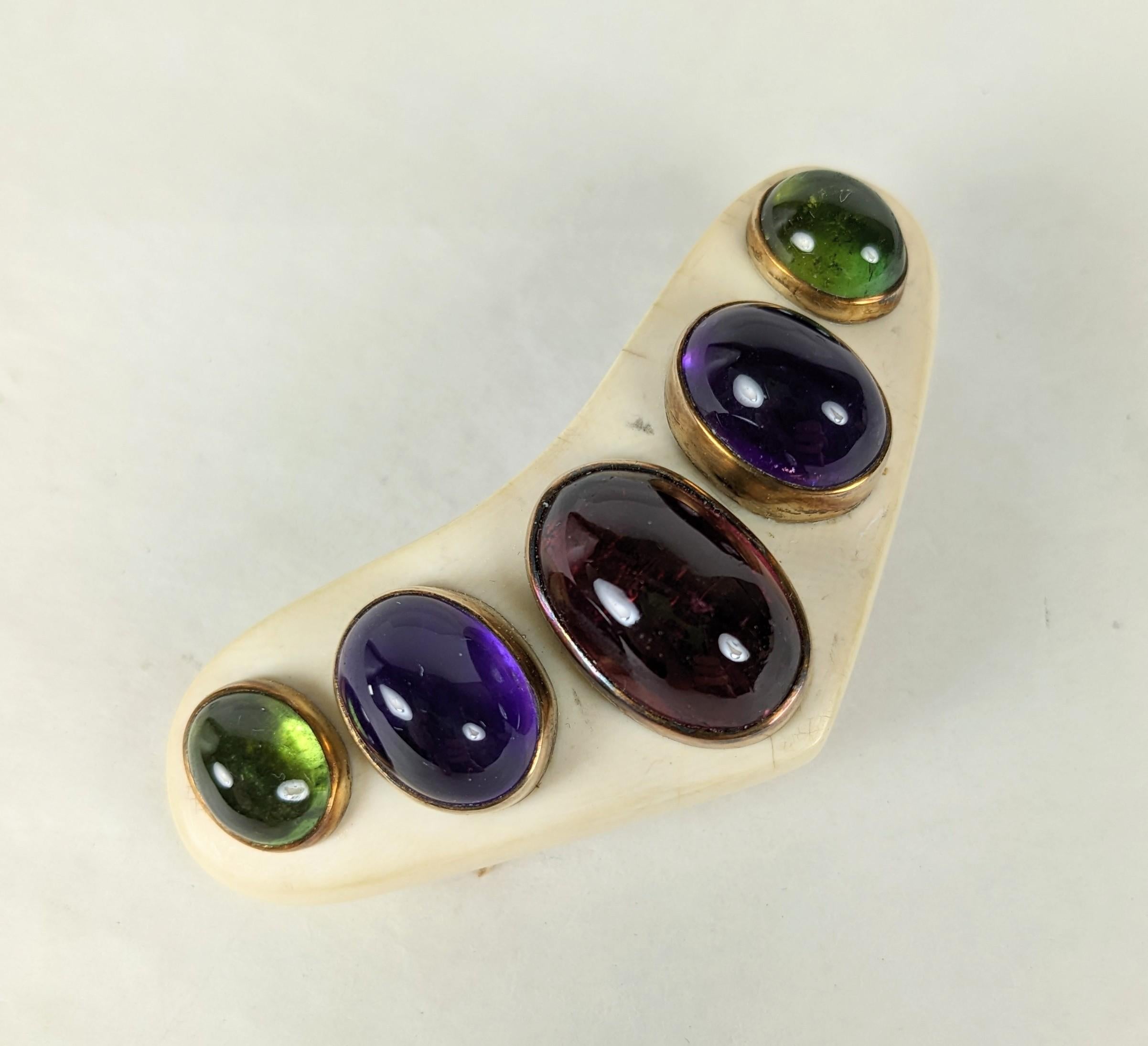 Gemstone Cabochon Boomerang Clip with a series of graduated oval cabochons set in 18k gold on a carved bone boomerang shaped clip brooch. Green and pink tourmalines are sued along with amythests. Maker: 18K with 