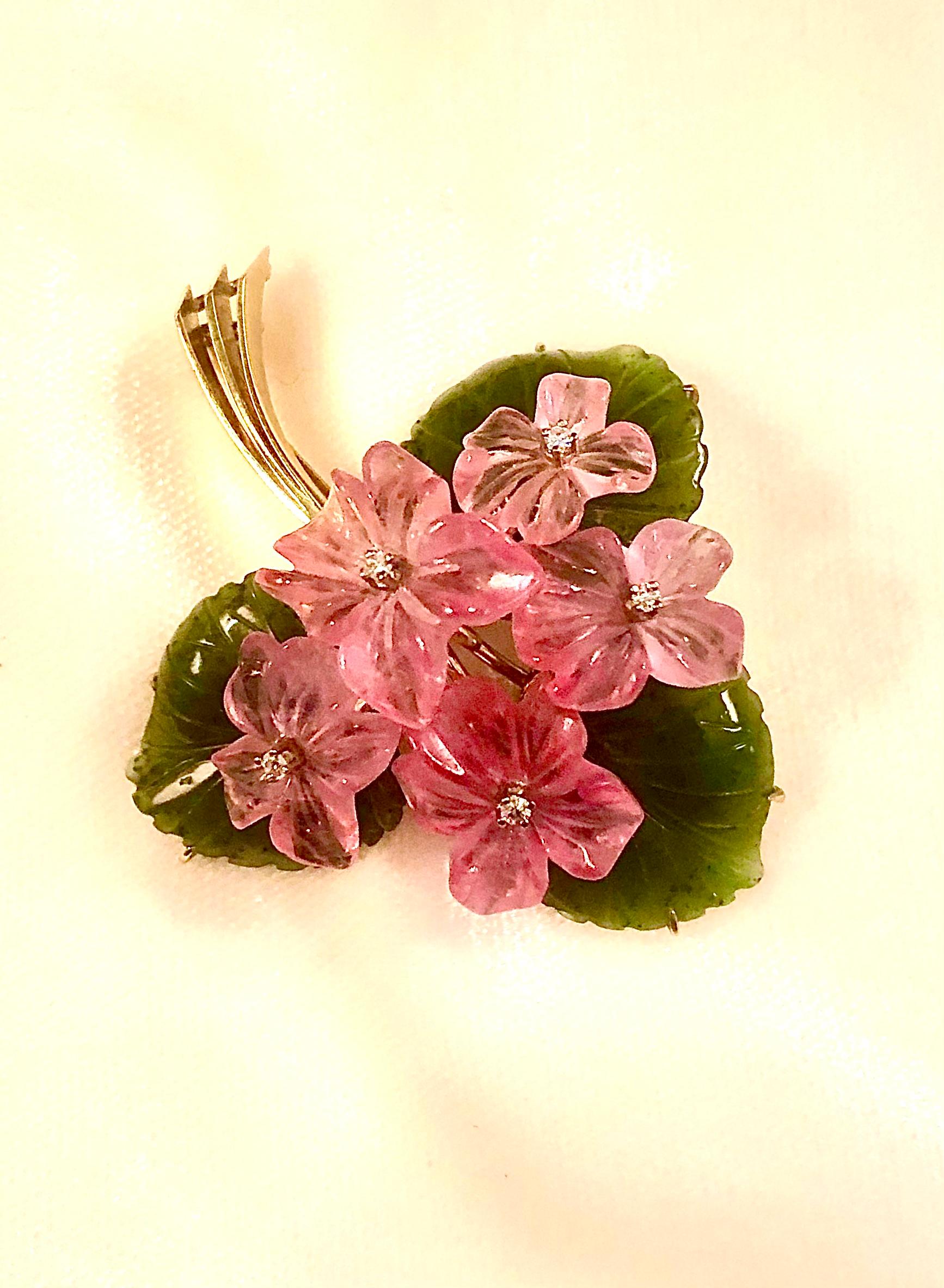 Bellissima spilla floreale con quarzo rosa finemente intagliato e pistilli di diamante taglio brillante. I fiori sono incastonati in foglie di giada nefrite ben intagliate.

L'intero pezzo è incastonato in una raffinata ed elaborata montatura in oro