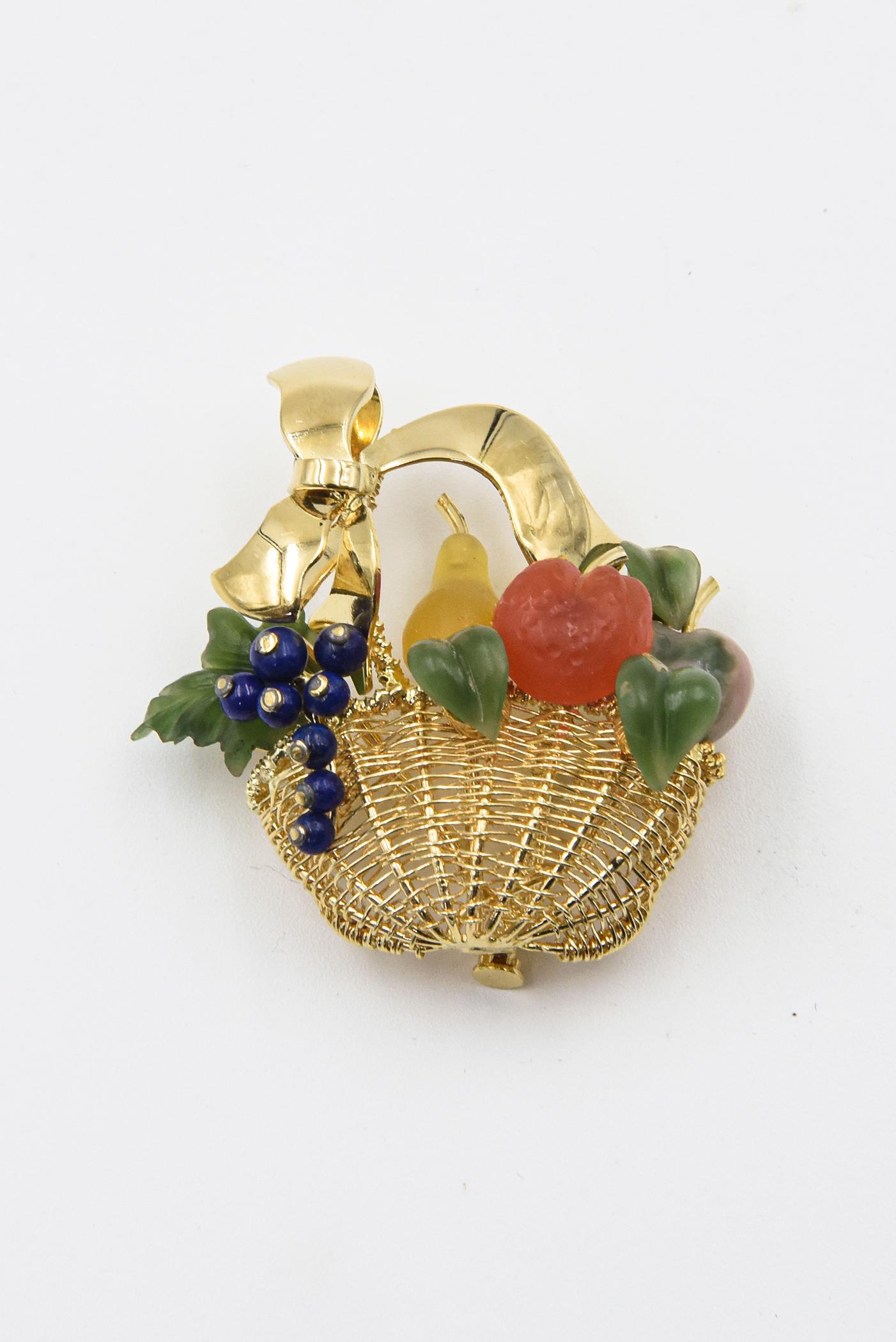 Beautiful fruit basket brooch has a carved pear, grapes, an apple and an orange with leaves as well.  The woven basket is 18k yellow with a bow handle.  The gemstones are chalcedony, quartz, lapis lazuli and jade.
