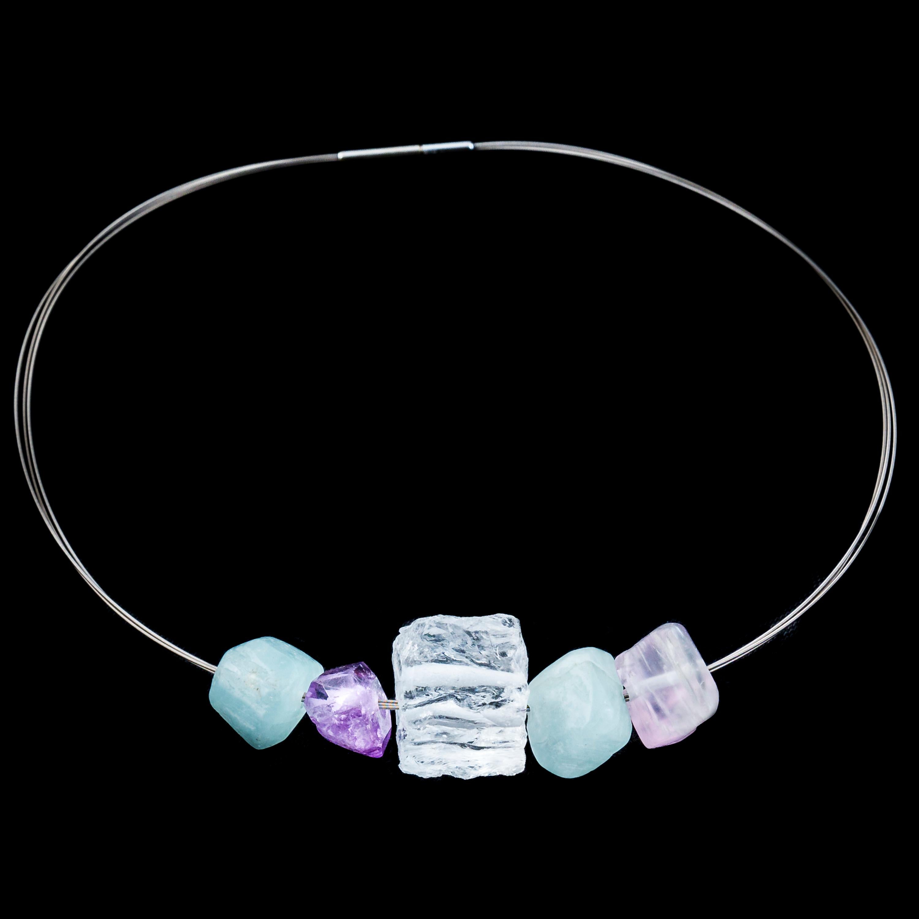 This unique multi gemstone necklace is strung with naturalistic beads of variously finished gemstones in soft, complimentary colours. 

The necklace features two aquamarine pieces, one amethyst piece, a clear rock crystal and a rose quartz. The