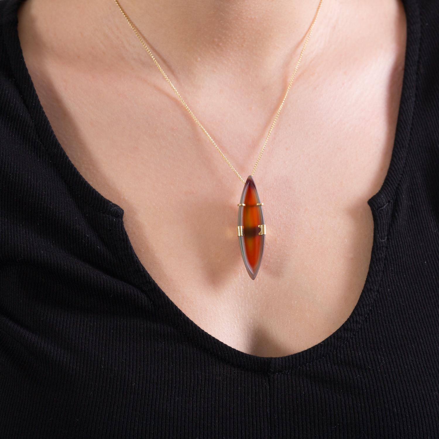 This one of a kind jewel is hand carved from an unusual amber and delicate green coloured Agate stone, formed into a soft boat shape, (carved by acclaimed lapidary artist Dieter Lorenz). Set in a minimalist 18 Karat gold setting to mirror the sleek