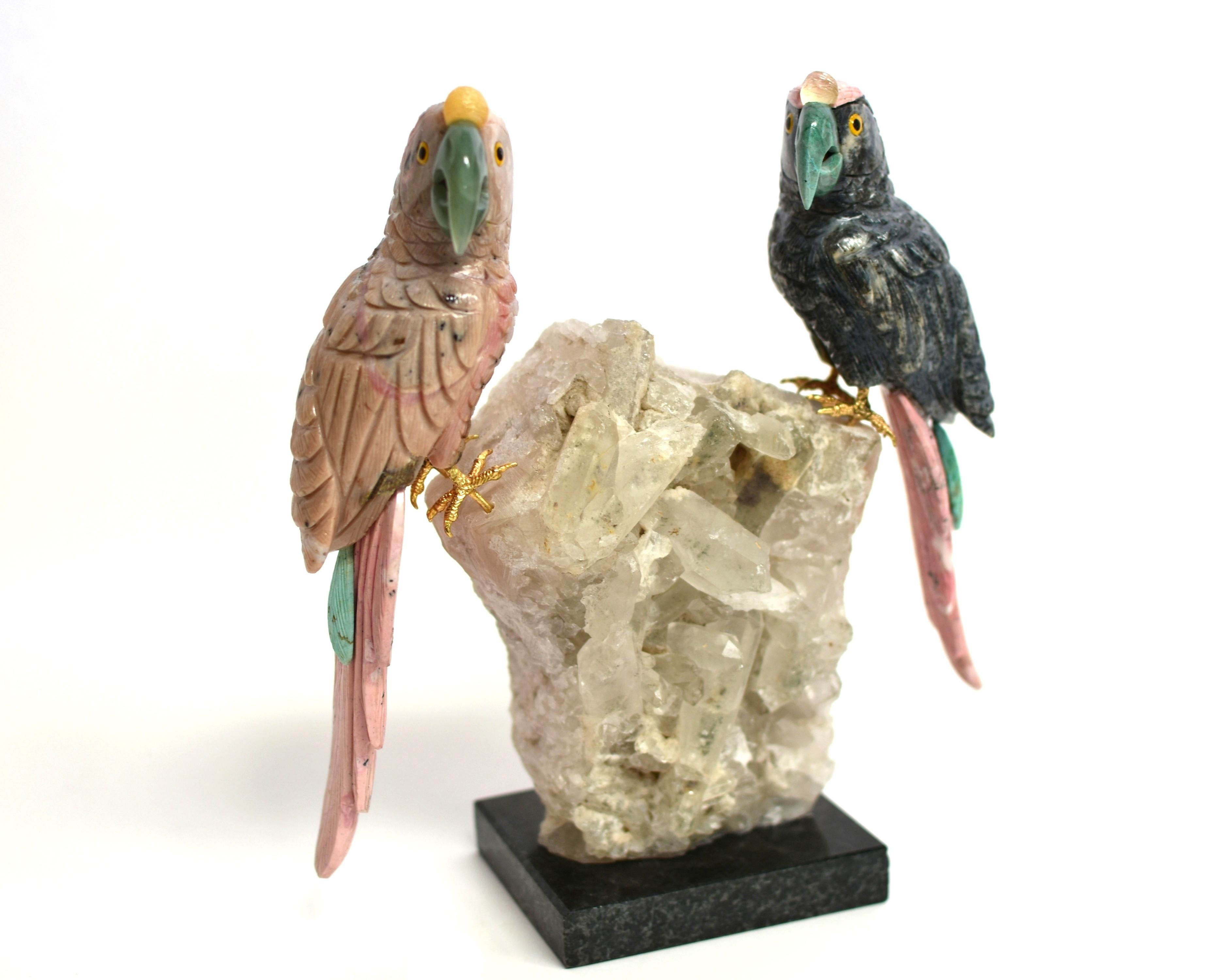 A finely carved, 7.8 lb, all natural multi-gemstone parrot sculpture. Naturalistically modeled perched on rock crystal clusters, the left bird with beautiful plumage made of pink opal and rhodonite with aventurine beak and orange calcite crown, the