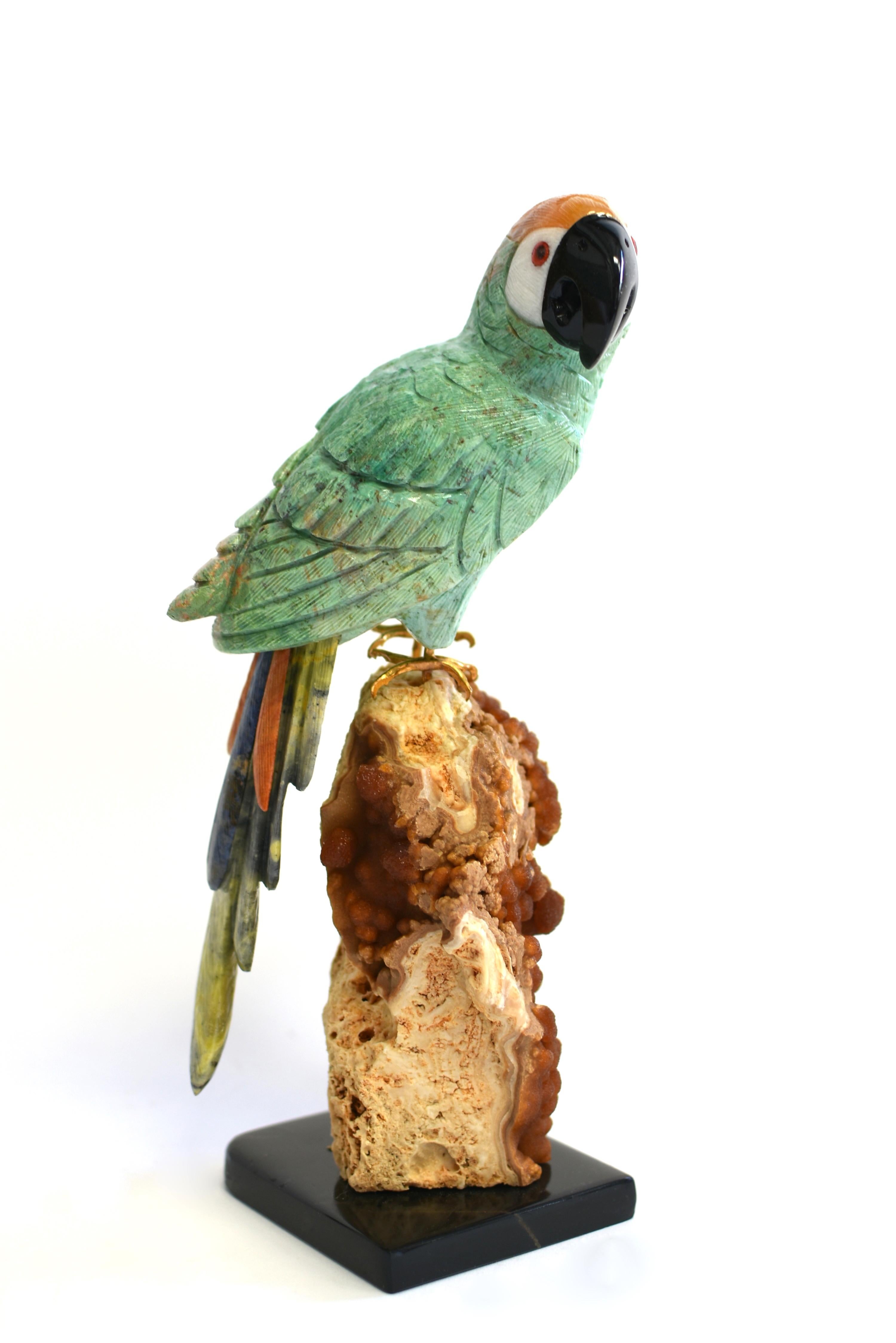 A beautiful gemstone Parrot on red jasper cluster on black marble base. Perched on jasper cluster, the parrot with turquoise amazonite plumage and tail in navy sodalite, orange jasper and green serpentine, the crown in agate and beak in black onyx.