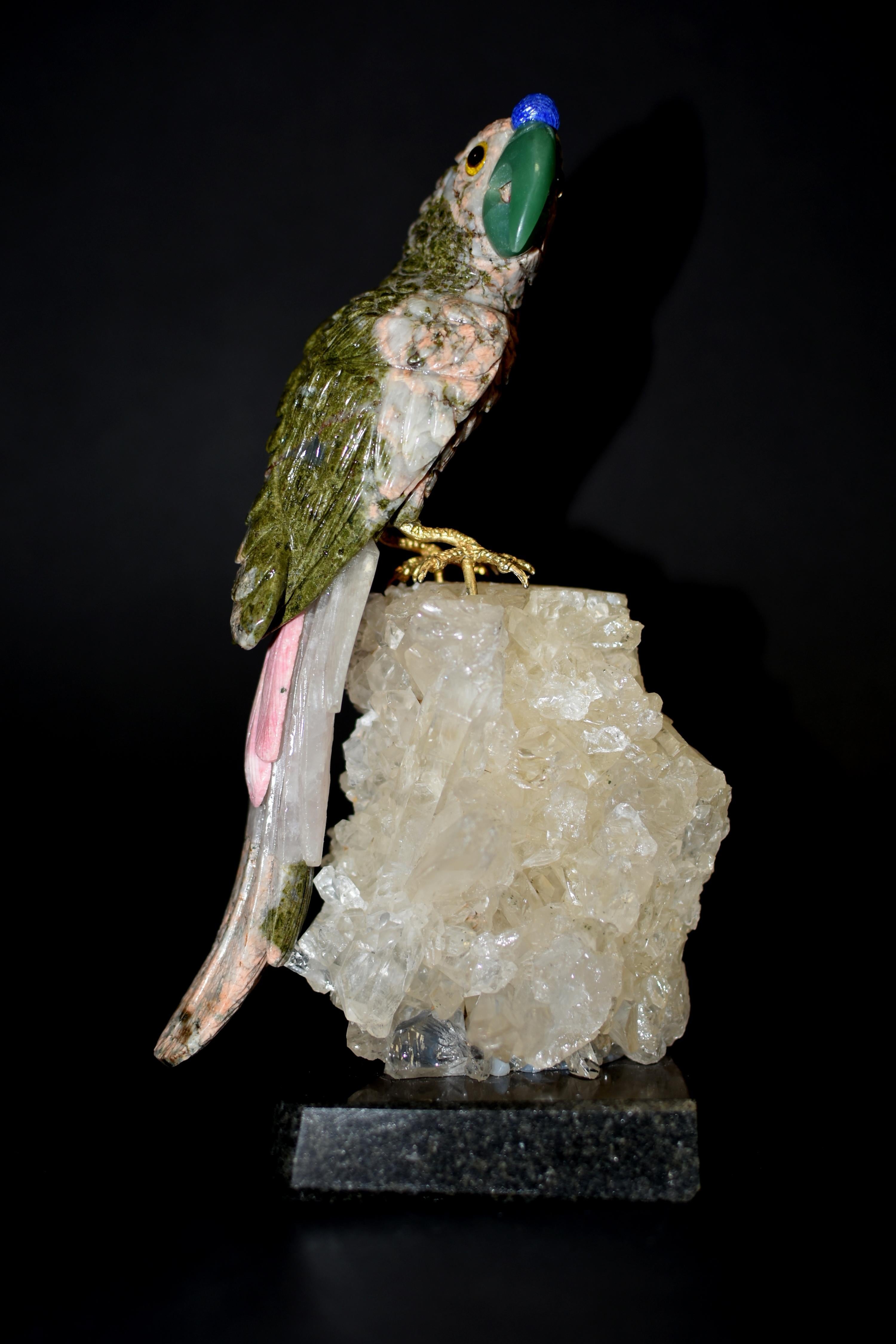 A finely carved gemstone parrot sculpture. Naturalistically modeled perched on rock crystal clusters, with beautiful plumage made of green gemstone unakite and pink redonite, an aventurine beak and blue sodalite crowning the forehead. The parrot