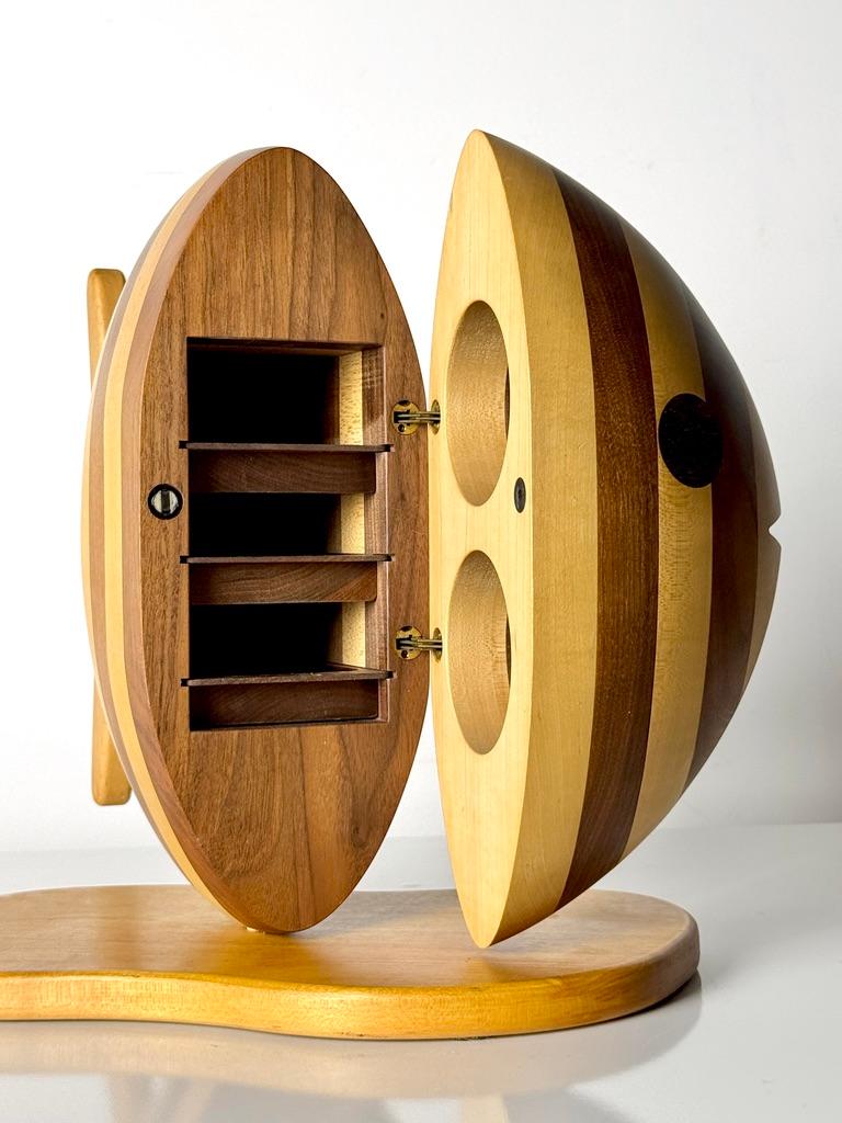 Scultura portagioie a forma di pesce di Gene Sherer 
USA 1984

Struttura in laminato di legno misto scolpito in una moderna forma di pesce
Il corpo si apre grazie a una cerniera magnetica nascosta, rivelando l'interno e 3 cassetti