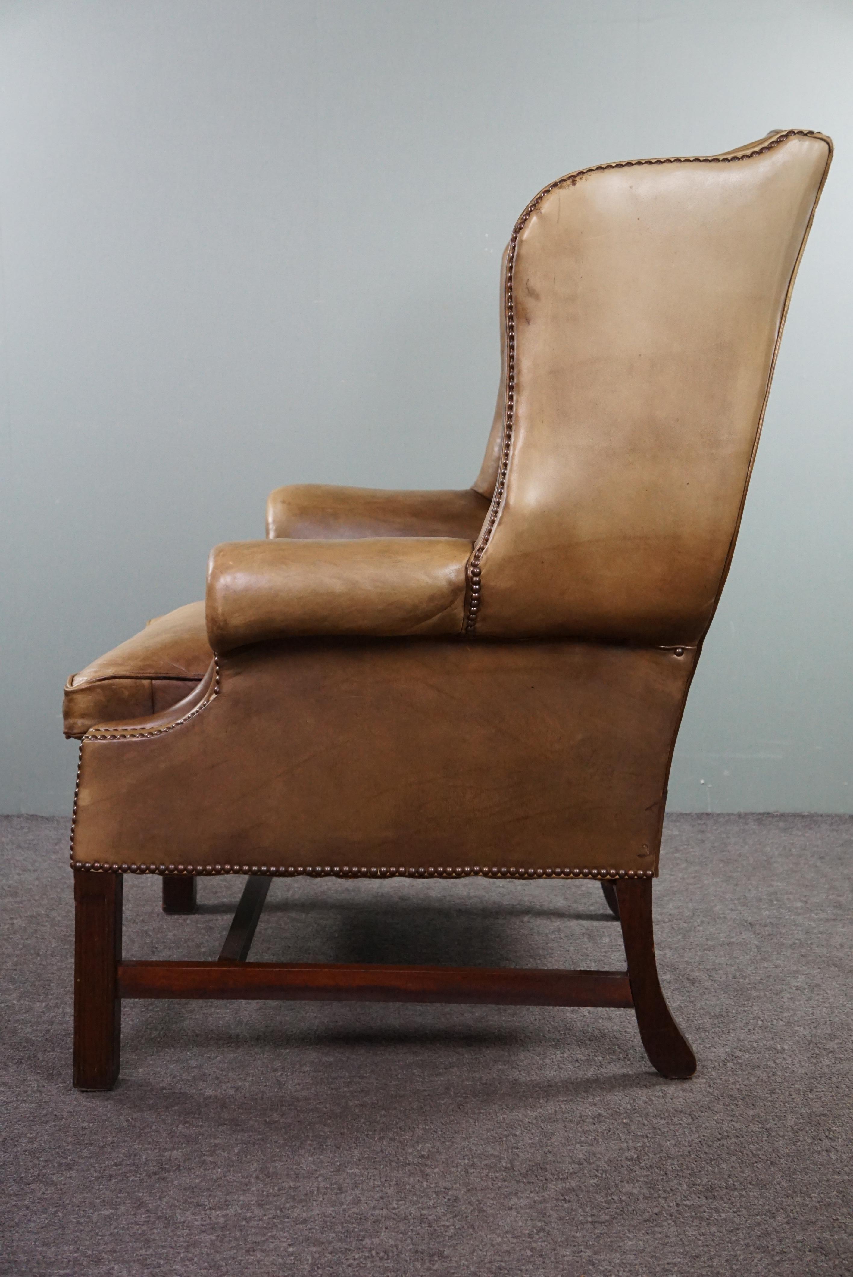 Cowhide Generous leather wingback armchair in very good condition.  For Sale