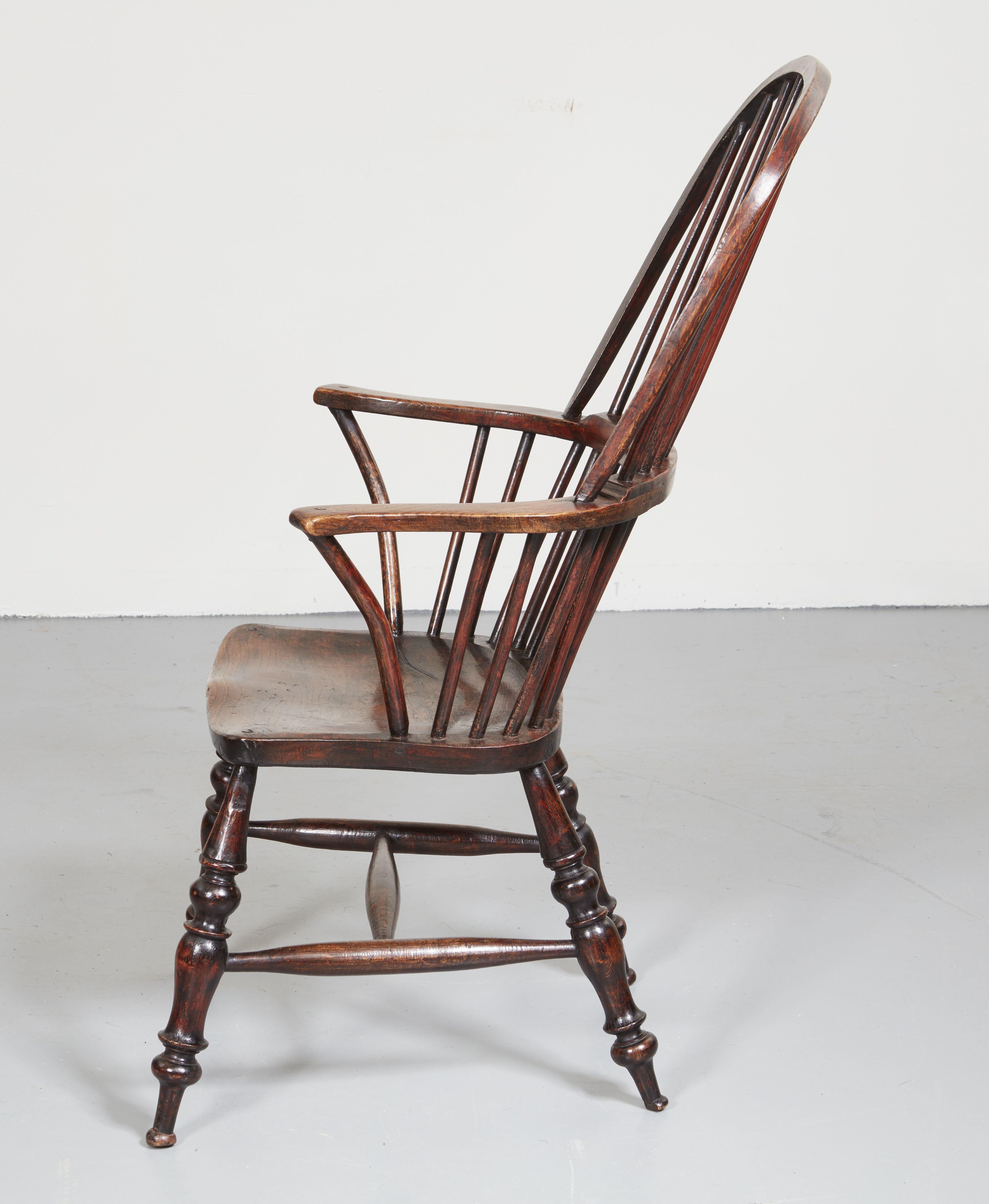 A generous and comfortable windsor armchair with excellent color. Features a high looped and raked back, flattened outswept arms, a saddled seat and boldly turned legs connected by an H stretcher.