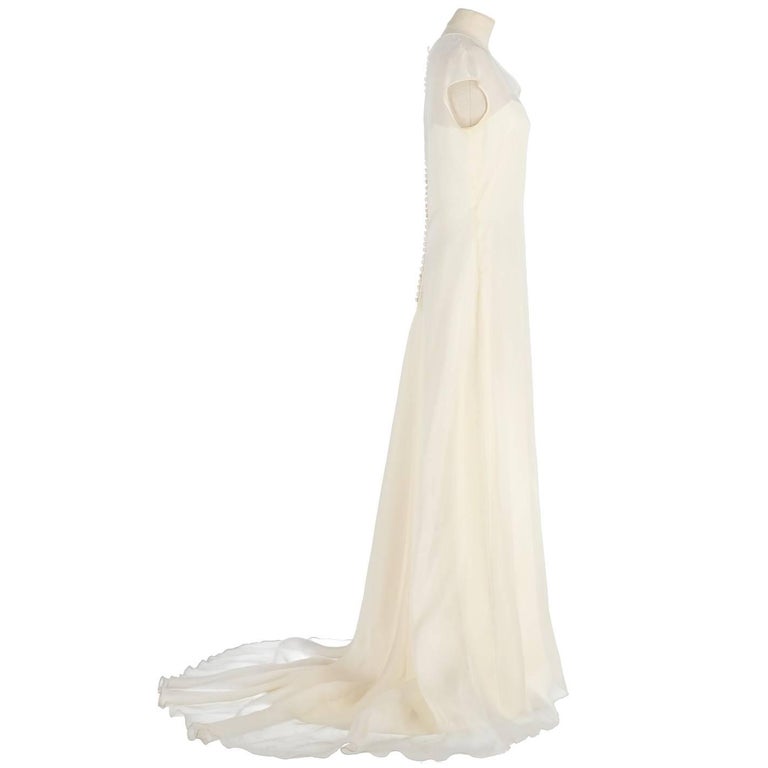Refined Genny wedding dress in white ivory silk. It features a silk veil dress with short sleeves and buttons closure on the back and a slipdress with super thin shoulder straps. The item is vintage, it was produced in the 90s and is in good