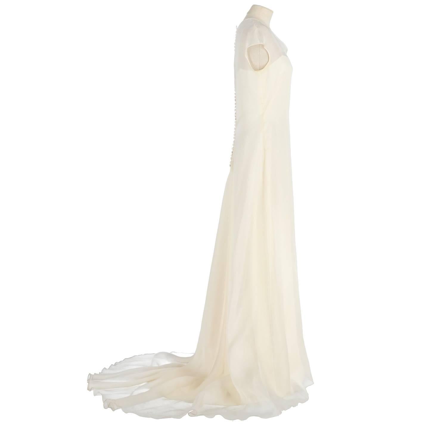Refined Genny wedding dress in white ivory silk. It features a silk veil dress with short sleeves and buttons closure on the back and a slipdress with super thin shoulder straps. The item is vintage, it was produced in the 90s and is in good