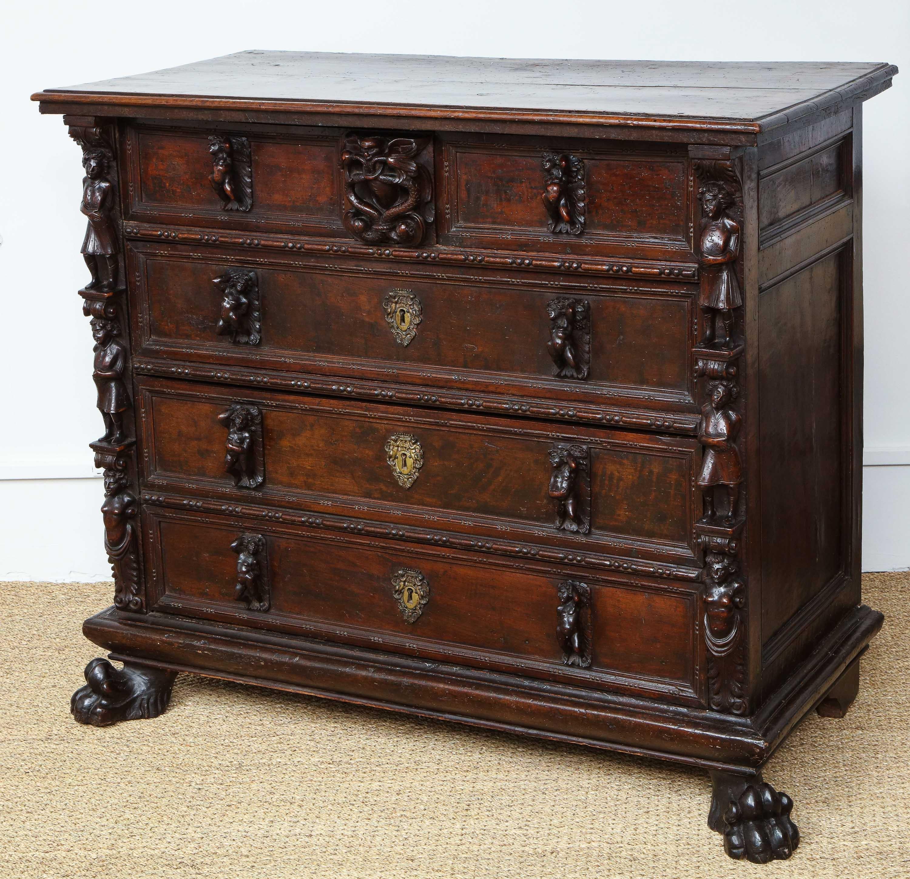 An Italian carved walnut chest of drawers ‘a bambocci', Genoese, early 17th century, the rectangular top with molded edge above four rows of frieze drawers, the central one with two vines and demon mask flanking two short and above three long