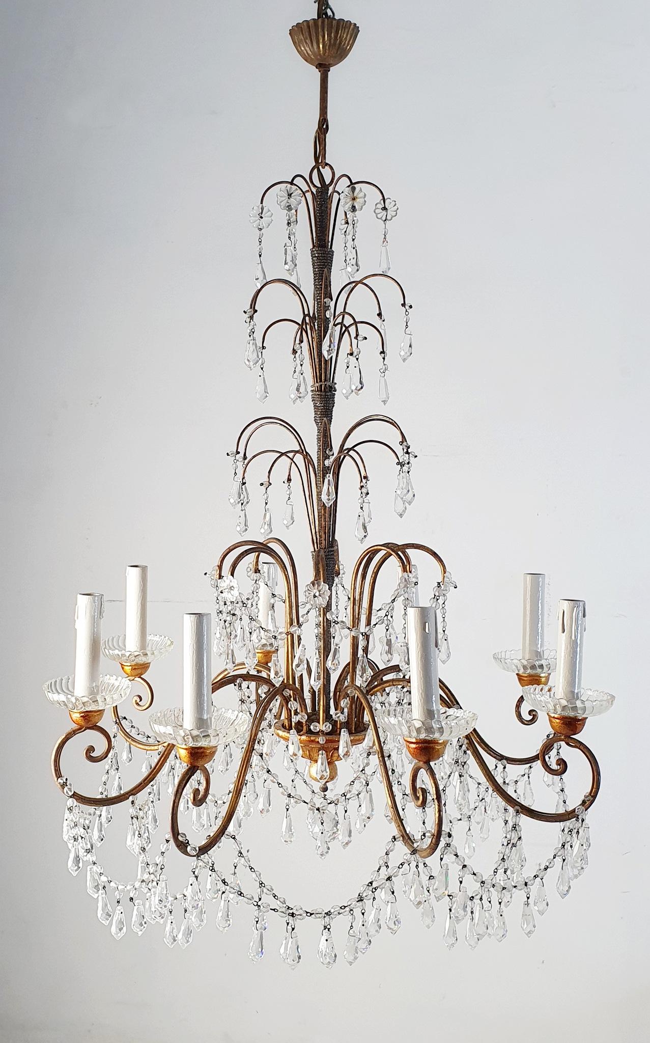 An Italian crystal chandelier in Empire style made with a guilded structure adorned with swags of crystals that glitter beautifully when lit up. This particular chandelier is free from decor apart from the guiliding, crystals and the beaded pearls