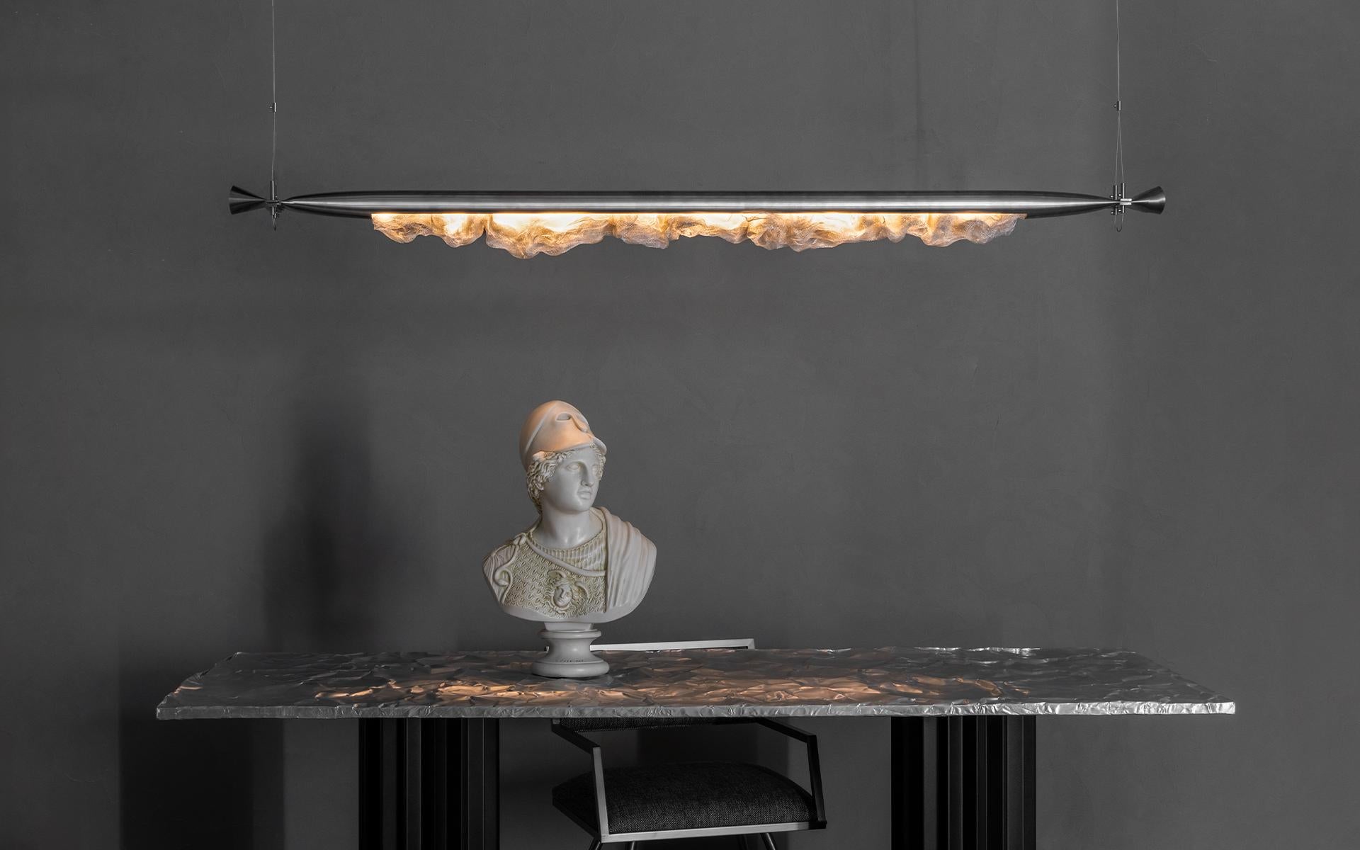 L'illuminazione Genshi è un pezzo unico che combina arte e design moderno. Realizzata in acciaio inossidabile, questa illuminazione attira l'attenzione con la sua superficie modellata da movimenti primitivi come la frantumazione, la piegatura e lo