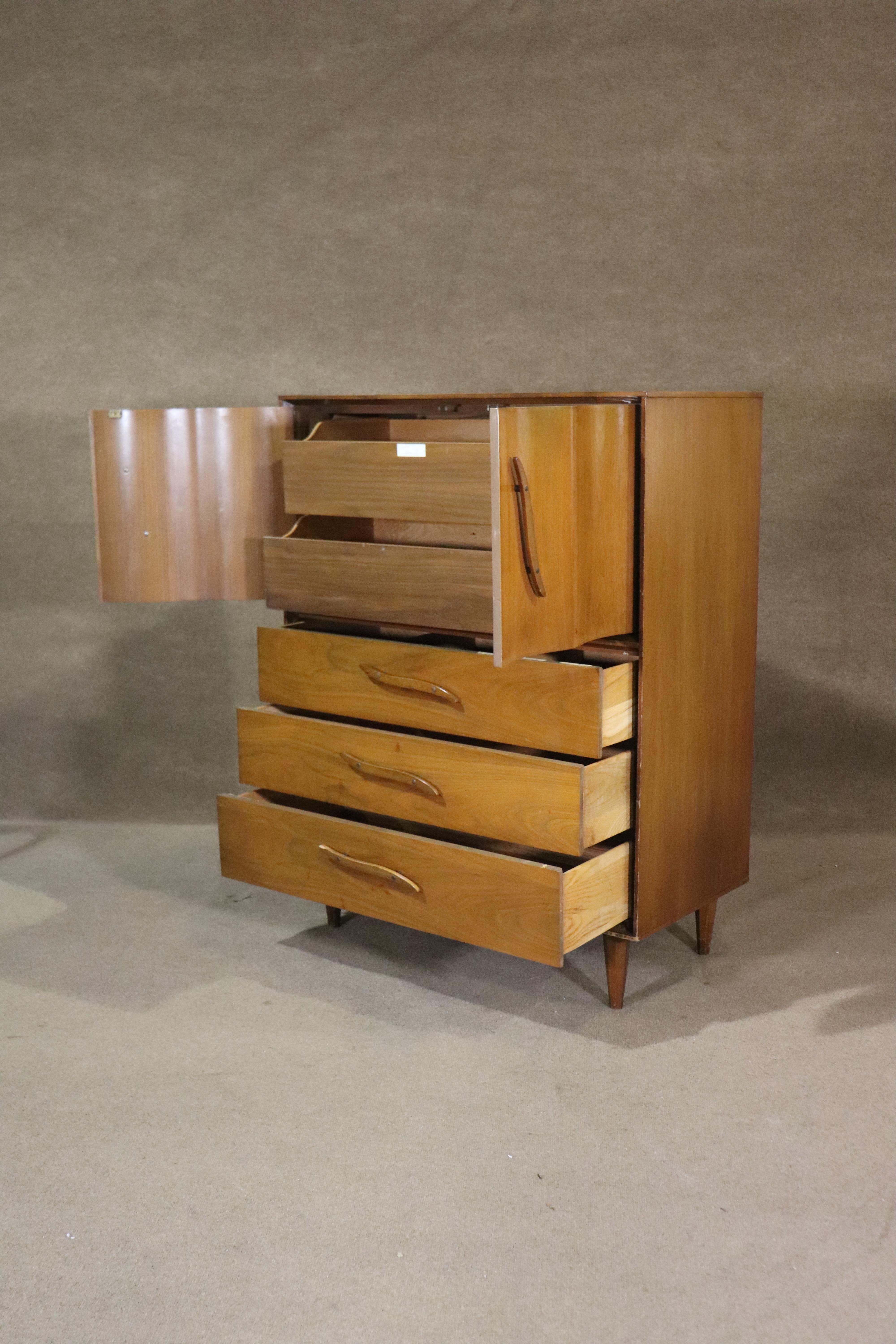Mid-century modern tall chest of drawers made by Unagusta Furniture. Five wide drawers, two hidden by wavy doors, with sculpted wood handles.
Please confirm location NY or NJ