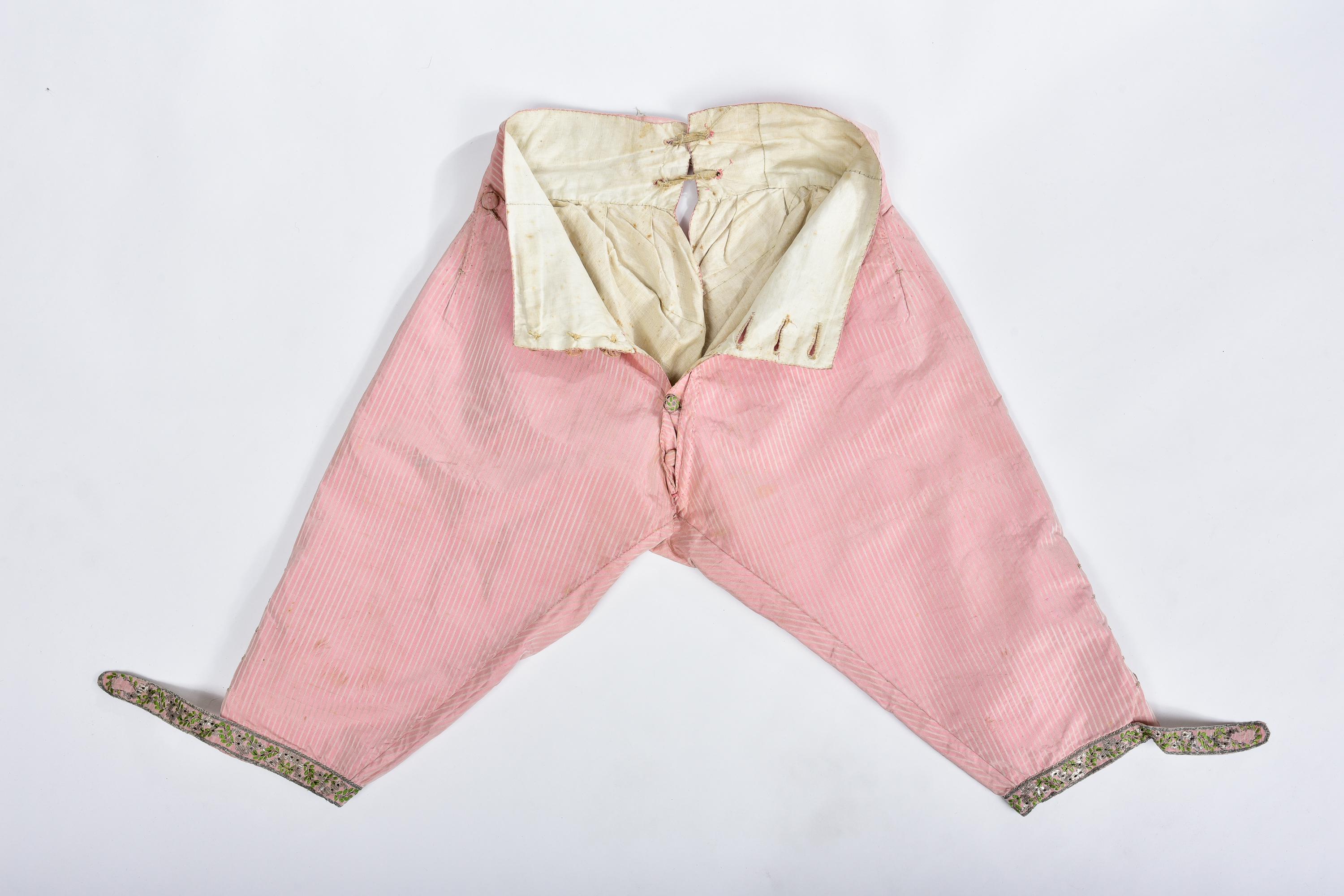 Circa 1780
France

Beautiful pink pekin silk breeches with white chevron stripes, probably for the Court. Rare model with buttoned fly complete with its buttons and one visible one is brocaded in coloured silk. Knee tabs in silver lamé brocade and