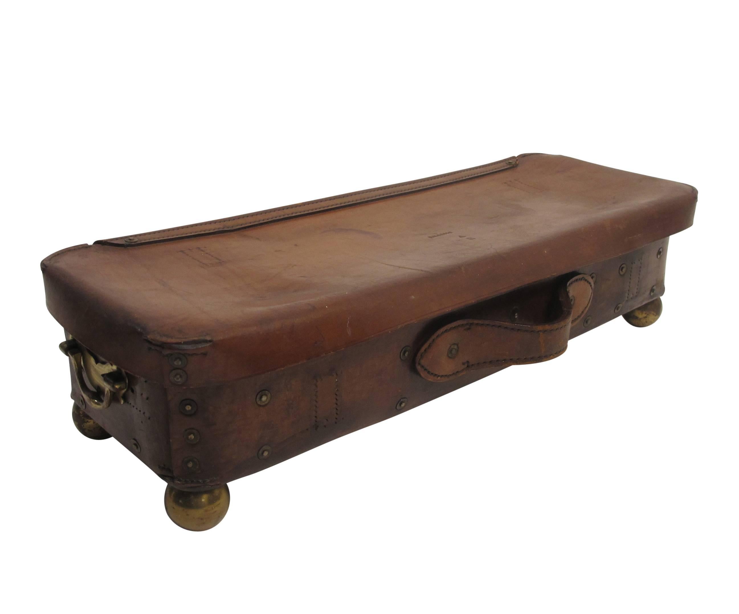 Large handsomely worn leather ammo box with felted interior and brass hardware, antique brass ball feet added at a later date. The interior lid having a monogram with crown, England, late 19th century.