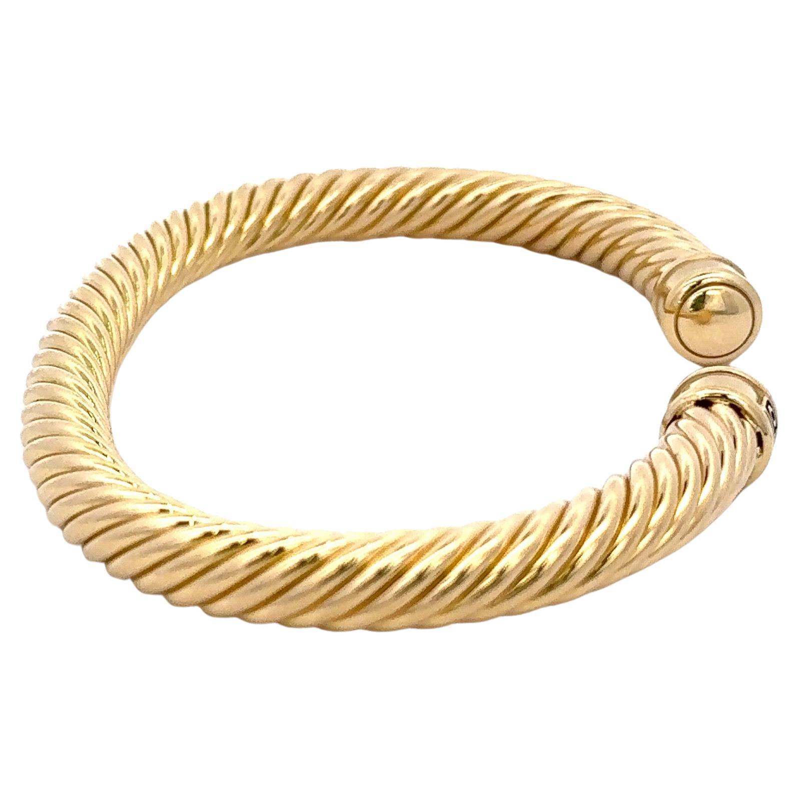 Ce bracelet David Yurman, de la série Cable Cuff Bangle, est réalisé en or jaune 18 carats et pèse 23,1 grammes. Il mesure 7 mm.