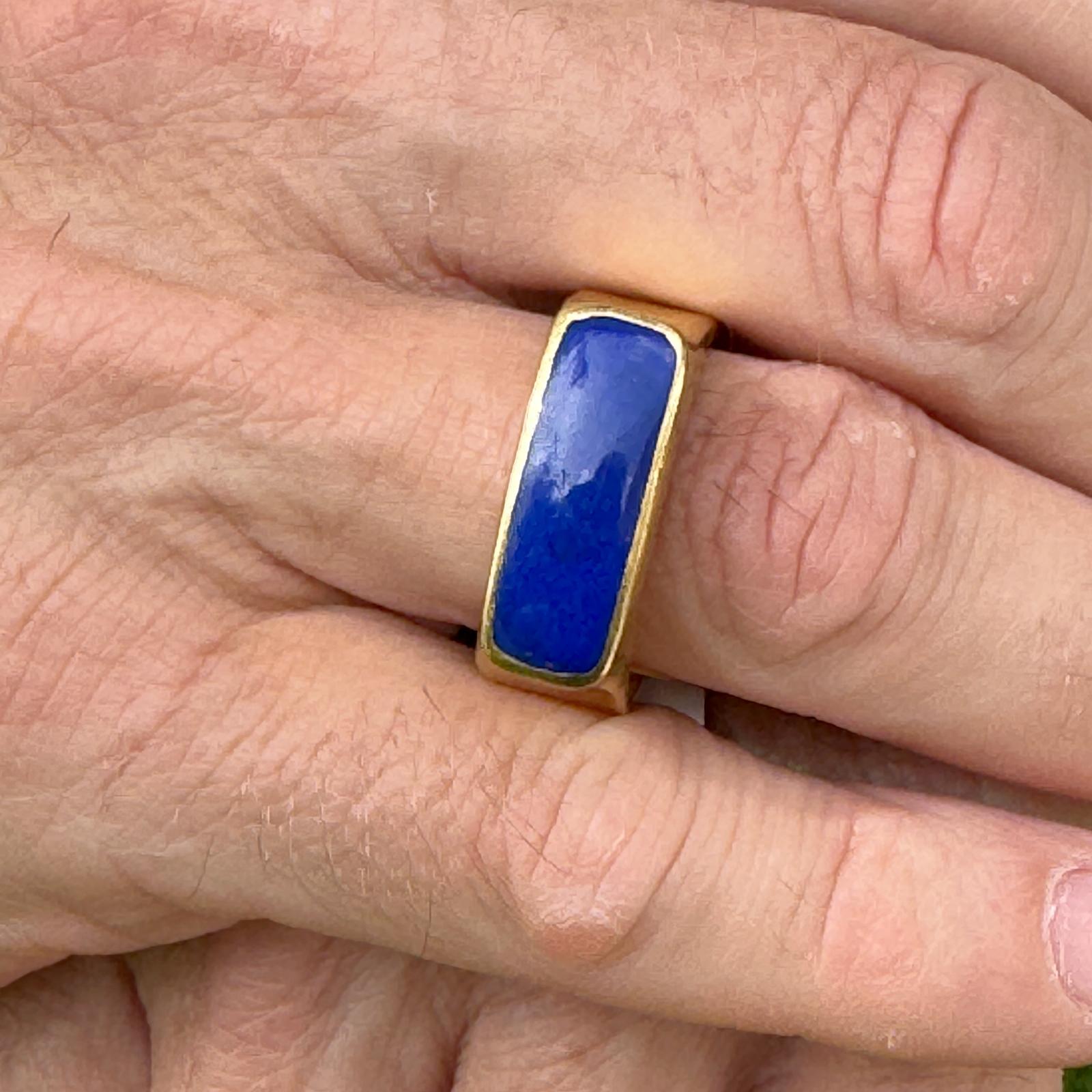 Gents lapis lazuli modern band ring handcrafted in solid 22 karat yellow gold. The ring features a cabochon lapis lazuli gemstone bezel set in a high polish artisan mounting. The ring is currently size 12 (can be sized) and measures 10mm in width.