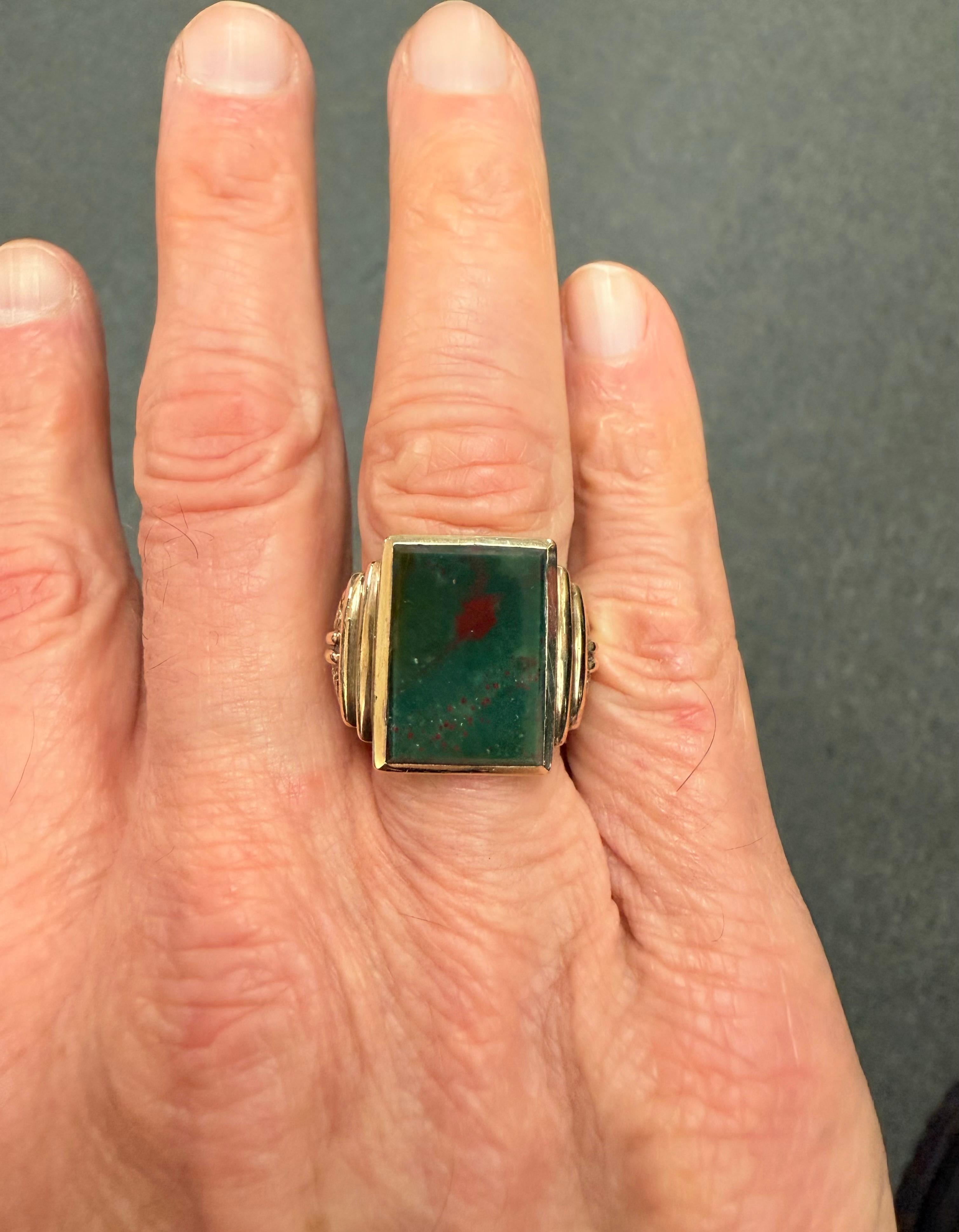 Anello da uomo in oro giallo 10k con pietra sanguigna d'epoca, circa 1930.

L'anello Vintage Bloodstone in oro giallo 10k per uomo è stato realizzato negli anni '30. Si tratta di un design rettangolare con grandi dettagli sul lato del gambo. La