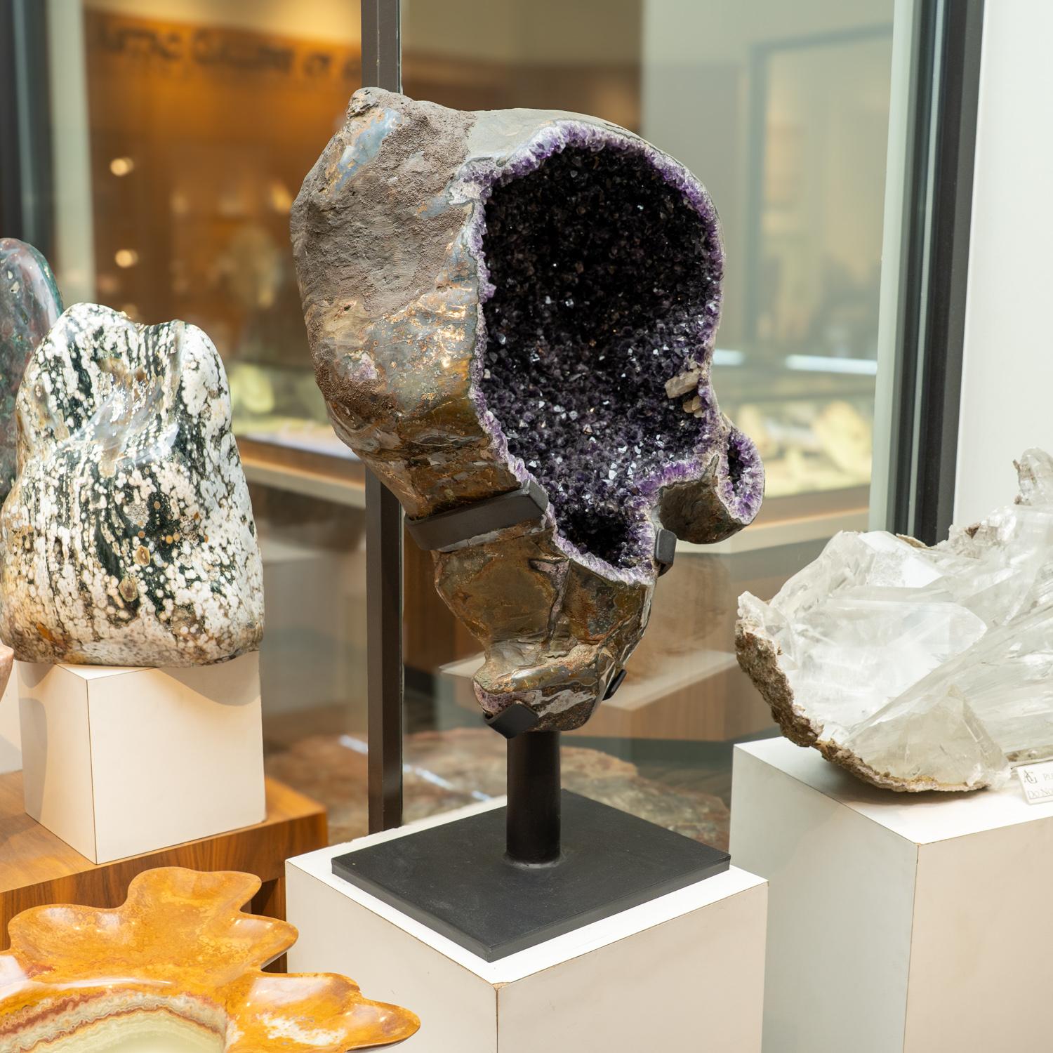 L'enorme geode di ametista, di qualità museale, presenta cristalli naturali, lucenti e completamente terminati, con facce altamente riflettenti e tonalità profonde, da trasparenti a traslucide. Questo bellissimo esemplare è dotato di un supporto