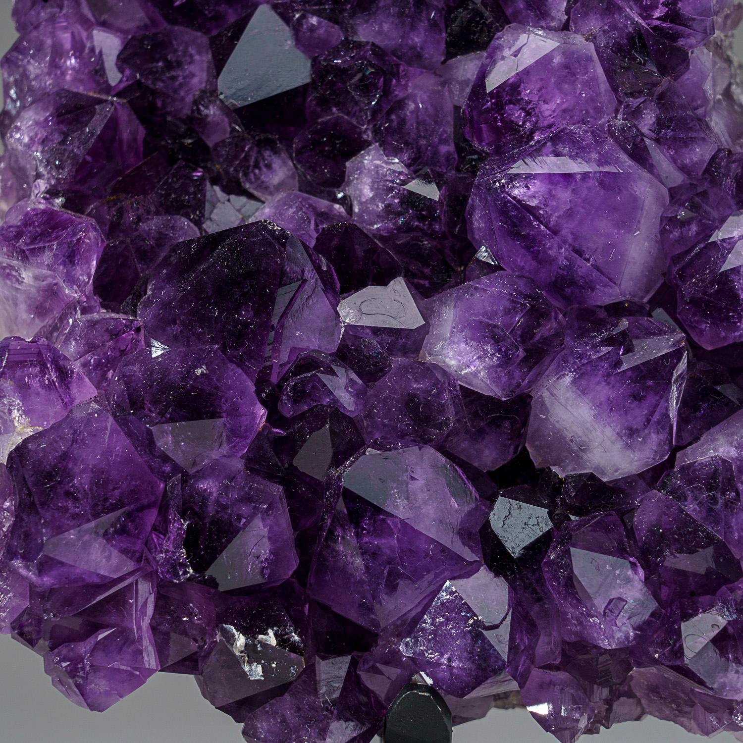 This AAA museum quality Amethyst Quartz Cluster features naturally formed, lustrous and fully terminated crystals with highly reflective faces and a deep, transparent to translucent hues. This beautiful specimen comes with a metal stand and is