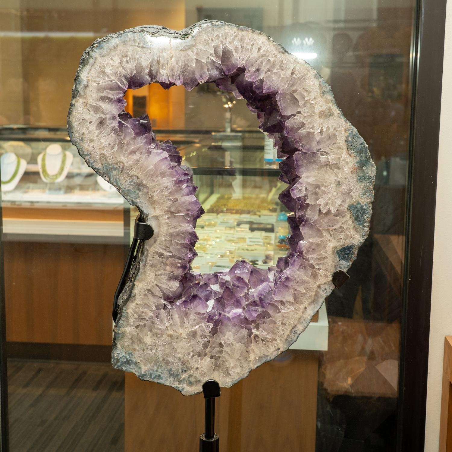 Questa fetta di geode di ametista di qualità museale presenta una forma naturale, lucente e completamente terminata con facce altamente riflettenti e tonalità profonde, da trasparenti a traslucide. Questo bellissimo esemplare è dotato di un supporto