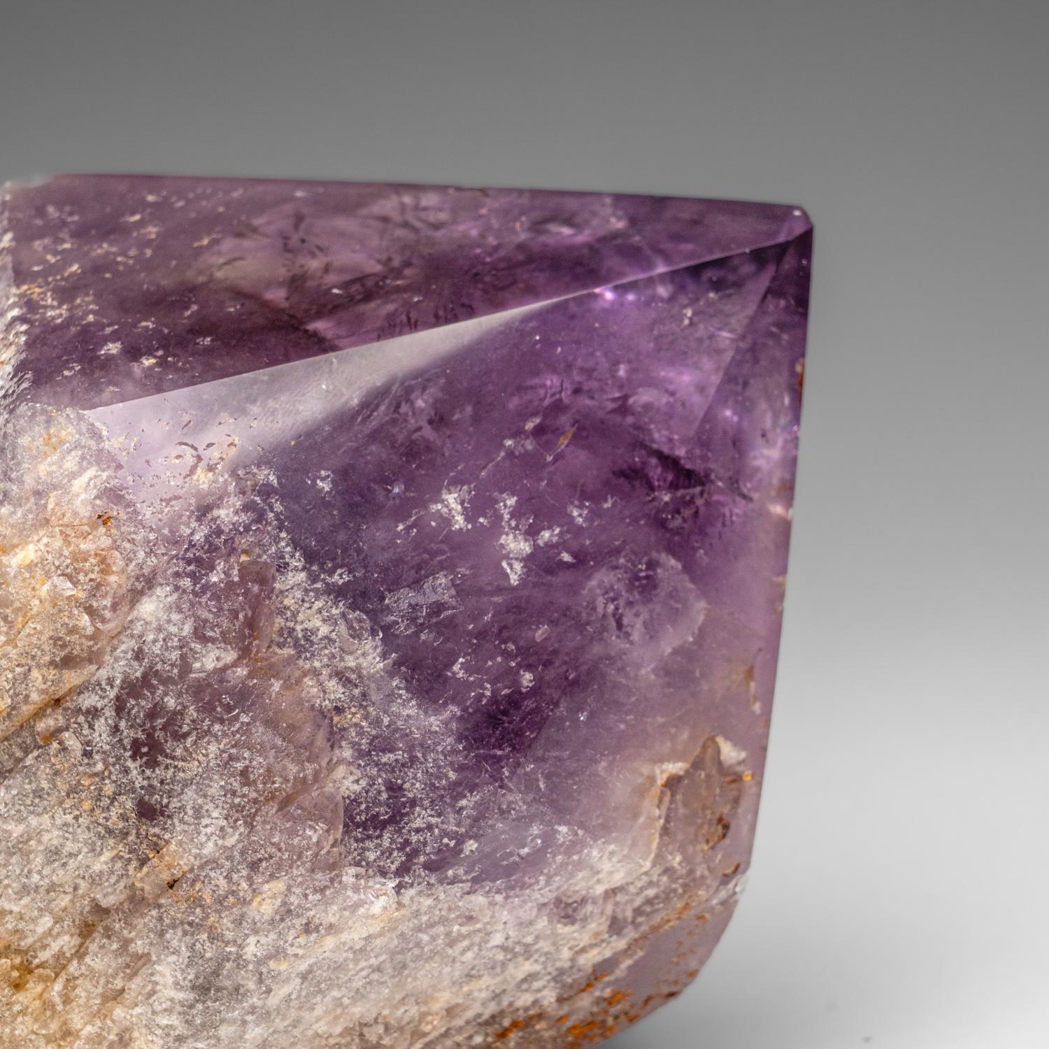 This is a natural amethyst crystal point sourced from Bolivia's Anahi Mine in the Santa Cruz Department. Its polished sides enhance the crystal's inherent termination. Amethyst, a form of quartz with traces of iron in its lattice, undergoes gamma