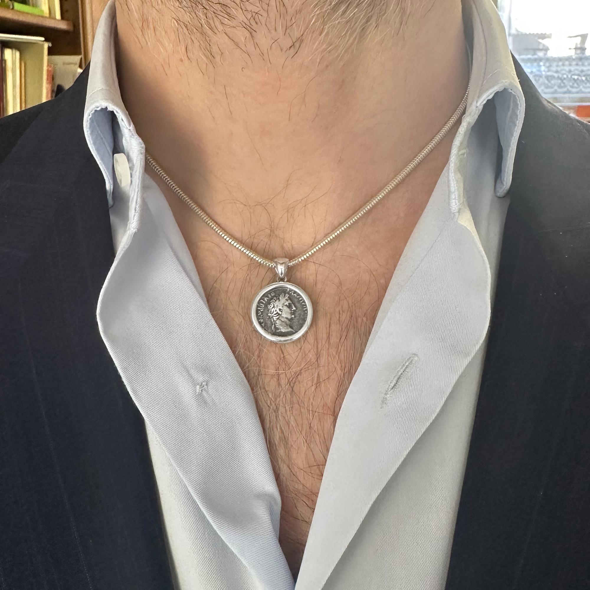 Entdecken Sie einen beeindruckenden Anhänger aus Sterlingsilber mit einer echten römischen Münze aus dem 1. Jahrhundert n. Chr. Dieses bemerkenswerte Stück zeigt das Porträt des Kaisers Augustus. Auf der Rückseite der Münze sind seine beiden Neffen