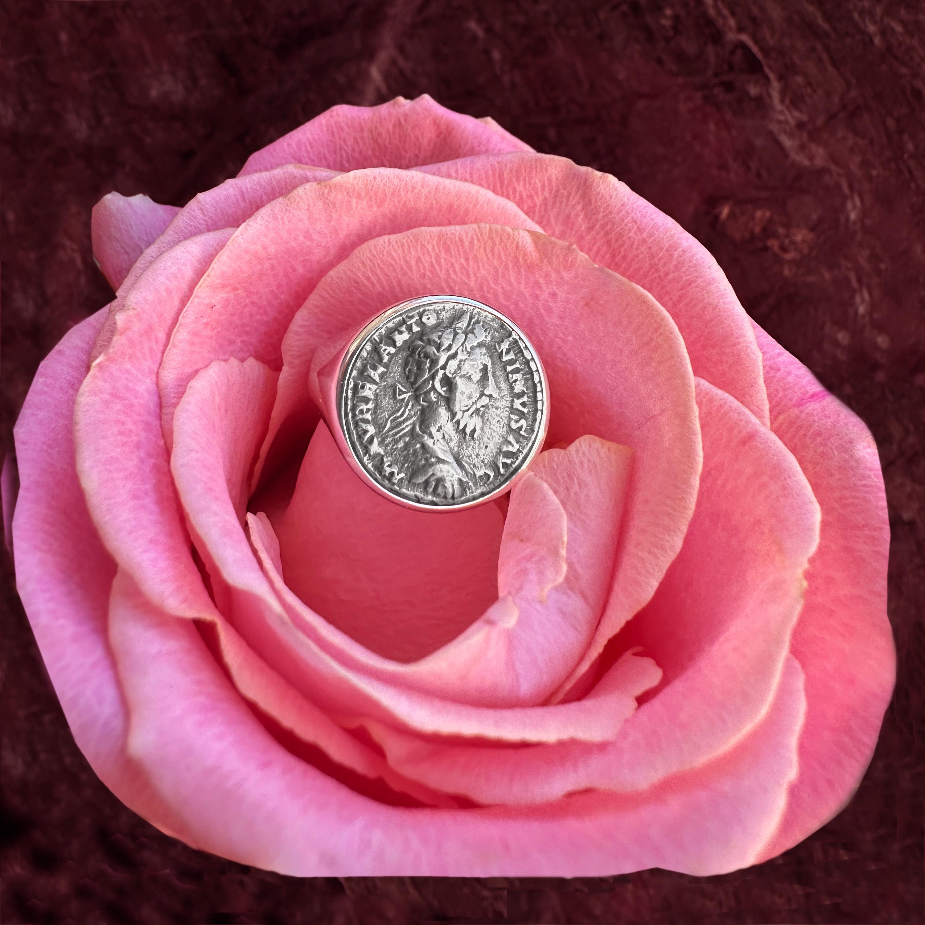 Questo squisito anello di monete presenta una moneta romana originale risalente al II secolo d.C., che raffigura l'imperatore Marco Aurelio. Il rovescio della moneta mostra una raffigurazione della Dea Fortuna.

Marco Aurelio, famoso sia come