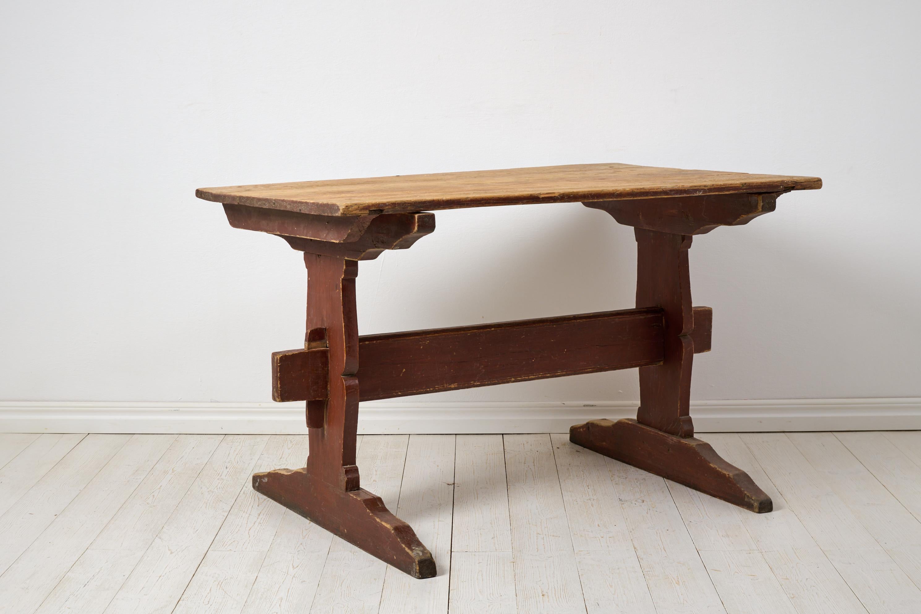 Antique rustic dining table or work table from northern Sweden, made around 1820. The table has a frame in solid pine that’s made by hand, completely without screws or nails. It is in original untouched condition with the original red-painted leg