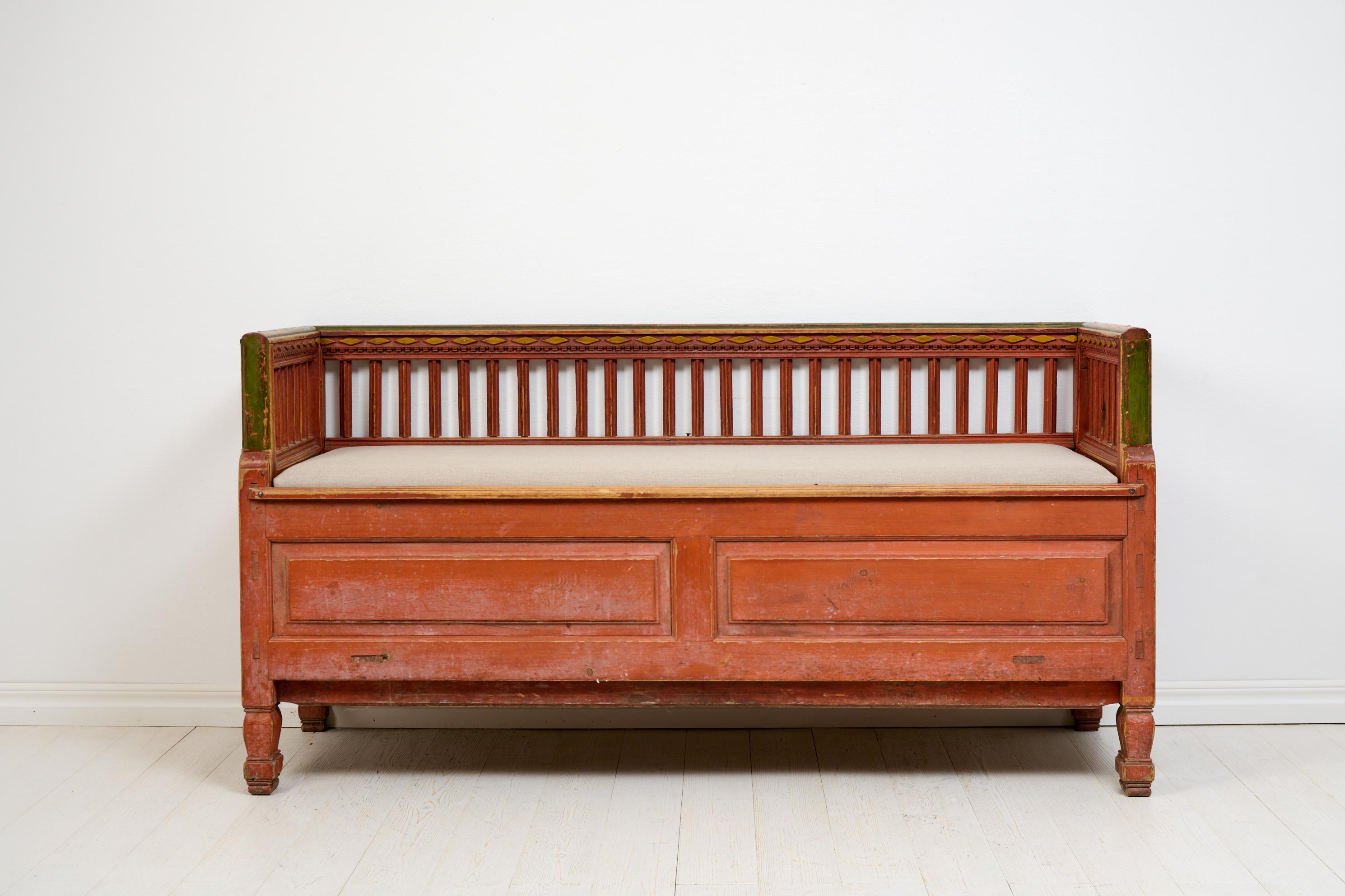 Rare folk art bench or sofa from northern Sweden, unusually well-crafted with decorative panels and sculpted legs. It features carved wooden decorations at the top of the backrest and was handcrafted in solid pine around 1820. The untouched original