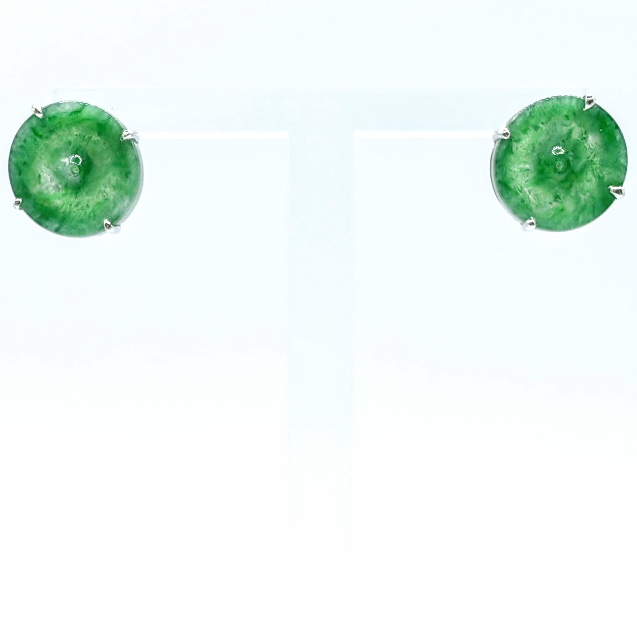 Questi squisiti orecchini a perno presentano due dischi di pace a ciambella di autentica giadeite verde ghiaccio birmana, ciascuno dei quali mostra un'eccezionale traslucenza e l'ambita tonalità verde vibrante che rende questa varietà di giada così