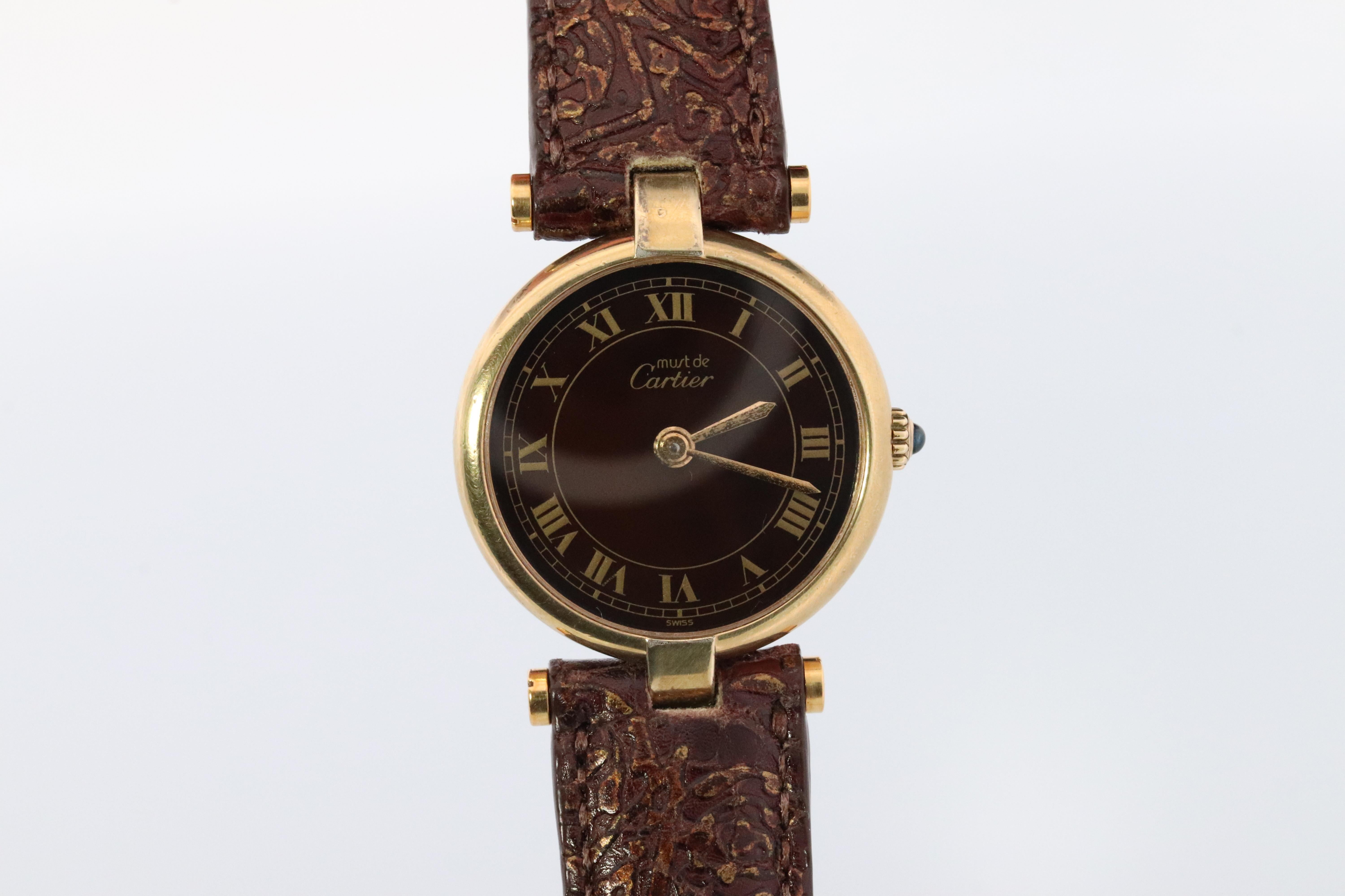 Genuine Cartier watch. 
Vintage Must de Cartier Vendome
Brown Face
Condition: Comes with Original Cartier case . Wear and tarnish consistent with age and normal wear.
New battery installed.

New brown leather handcrafted strap.
Details:

24mm Round