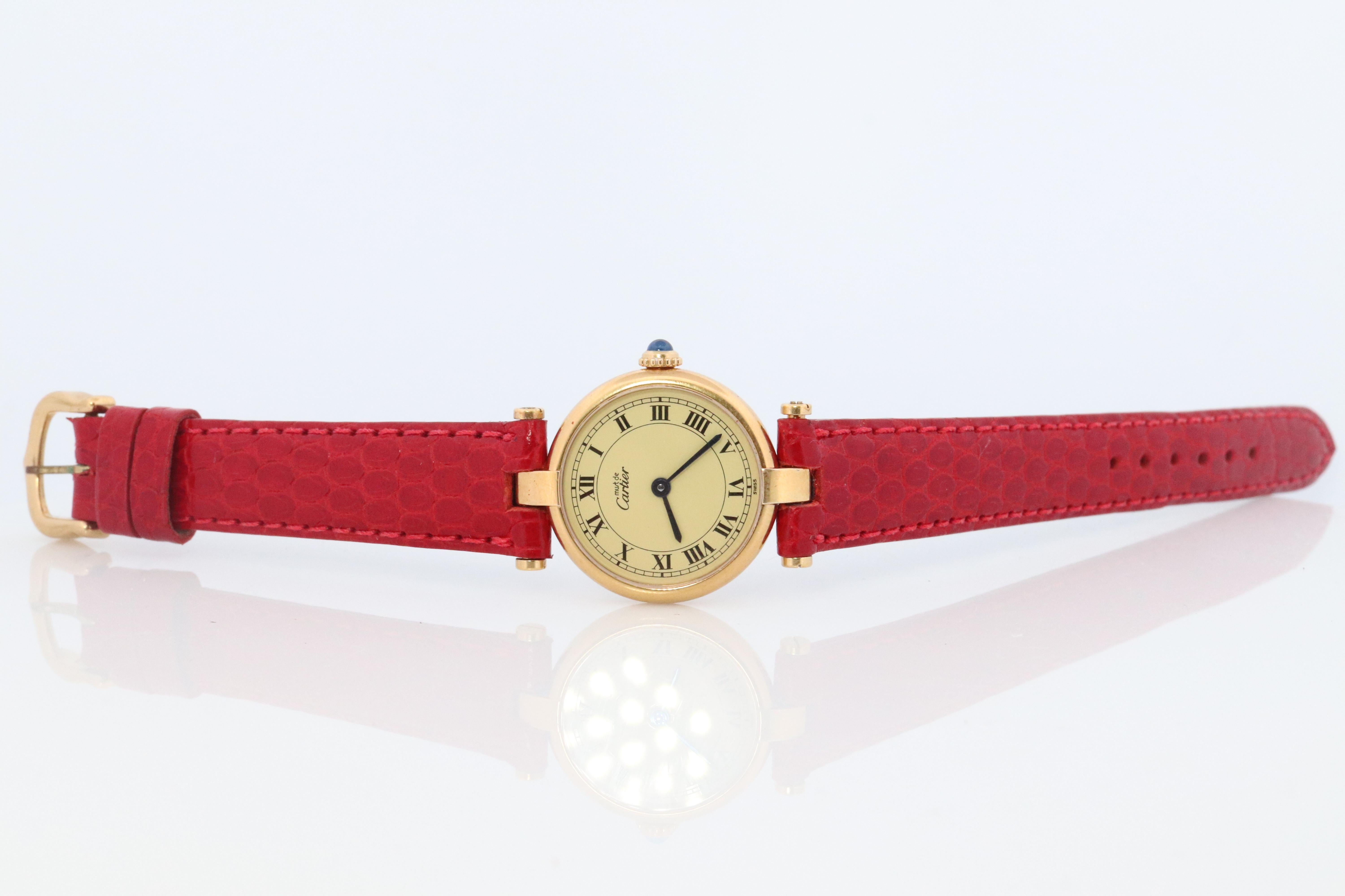 Echte Cartier Uhr.

Vintage Must de Cartier Vendome

Seltene Creme Zifferblatt.

Saphir-Cabochon-Krone.

Zustand: Altersgemäße Abnutzung. Neues rotes Echtlederband.
Neue Batterie installiert.

Einzelheiten:
24mm Rundes Gehäuse