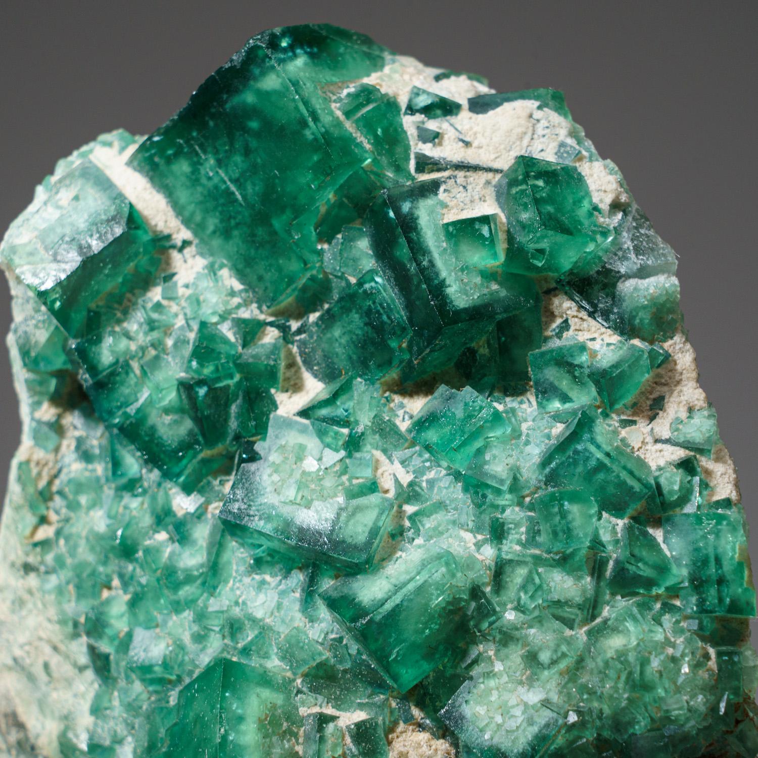 Transparente grüne kubische Fluoritkristalle mit leicht strukturierten Kristallflächen, die aus mikroskopisch kleinen oktaedrischen Flächen bestehen. Die leuchtend grüne Farbe ist sehr gut für diese klassische Fundstelle, die normalerweise dunkleren