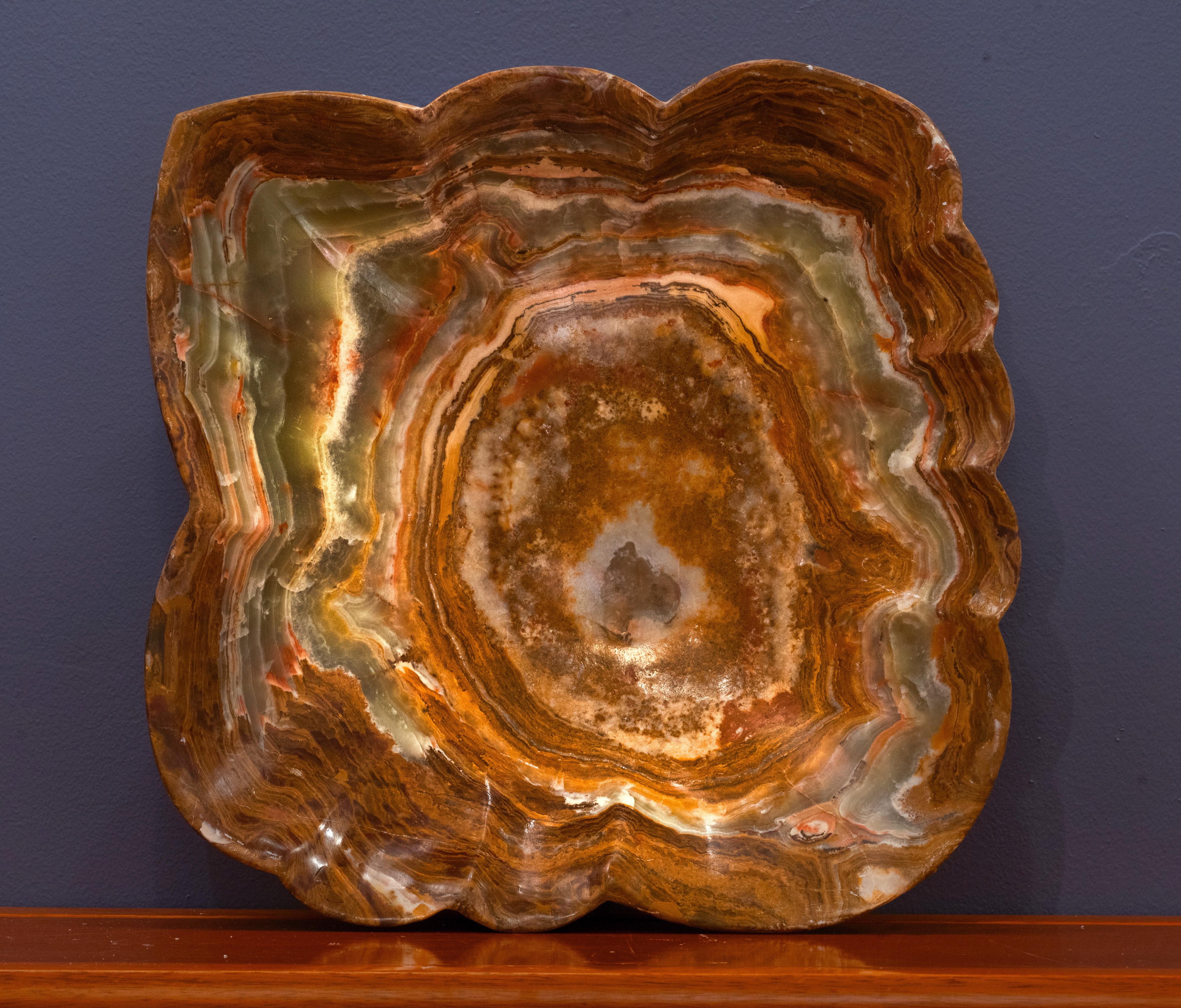 This gorgeously hand-carved 20.5 pound genuine banded onyx freeform bowl from Pakistan features intensely pigmented earthy green and rich brown bands and swirls accented by contrasting tan. This dynamic bowl – the perfect size for a large