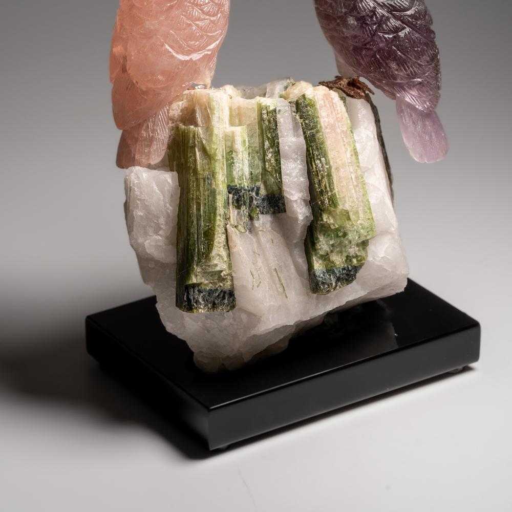 Questa scultura di gufo è un pezzo d'arte unico, scolpito in fluorite e quarzo rosa di qualità museale con occhi in onice e becco in corniola. Il gufo è appollaiato in cima a una matrice di tormalina verde e quarzo e montato su un supporto