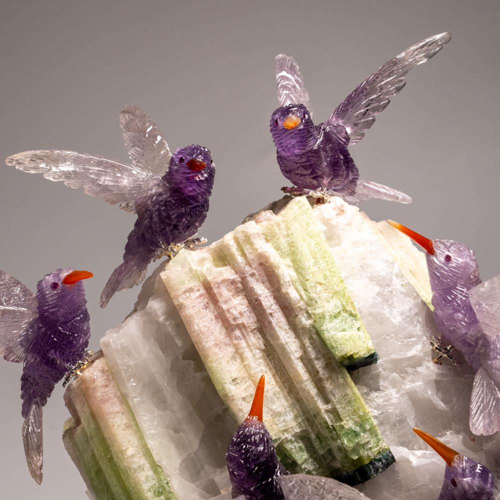 Cette sculpture de colibri est une pièce d'art unique, sculptée dans de la fluorine de qualité musée, avec des yeux en onyx et un bec en cornaline. Le hibou est perché au sommet d'une matrice de tourmaline verte et de quartz et monté sur un support