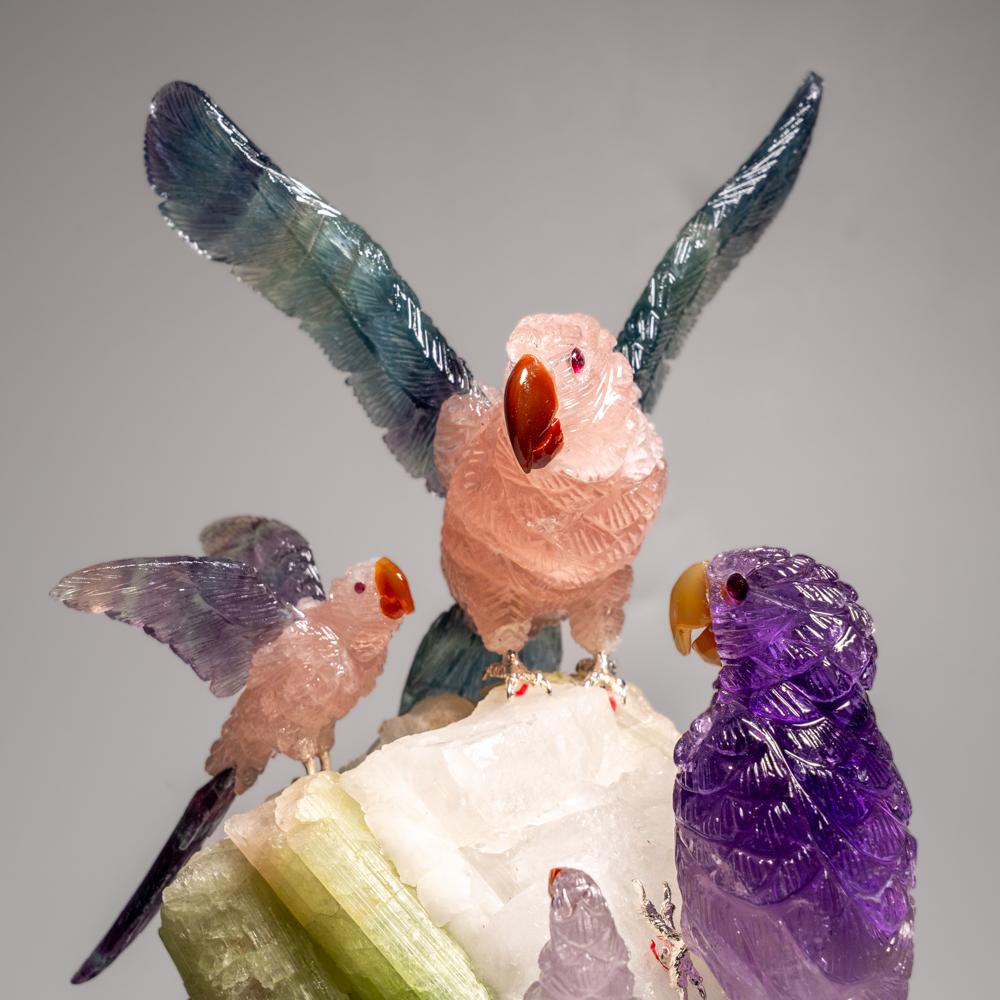 This Parrots carving is a unique piece of art, carved from museum-quality fluorite and rose quartz with onyx eyes and a carnelian beak. The parrots is perched atop a green tourmaline and quartz matrix and mounted on a custom stand for convenient