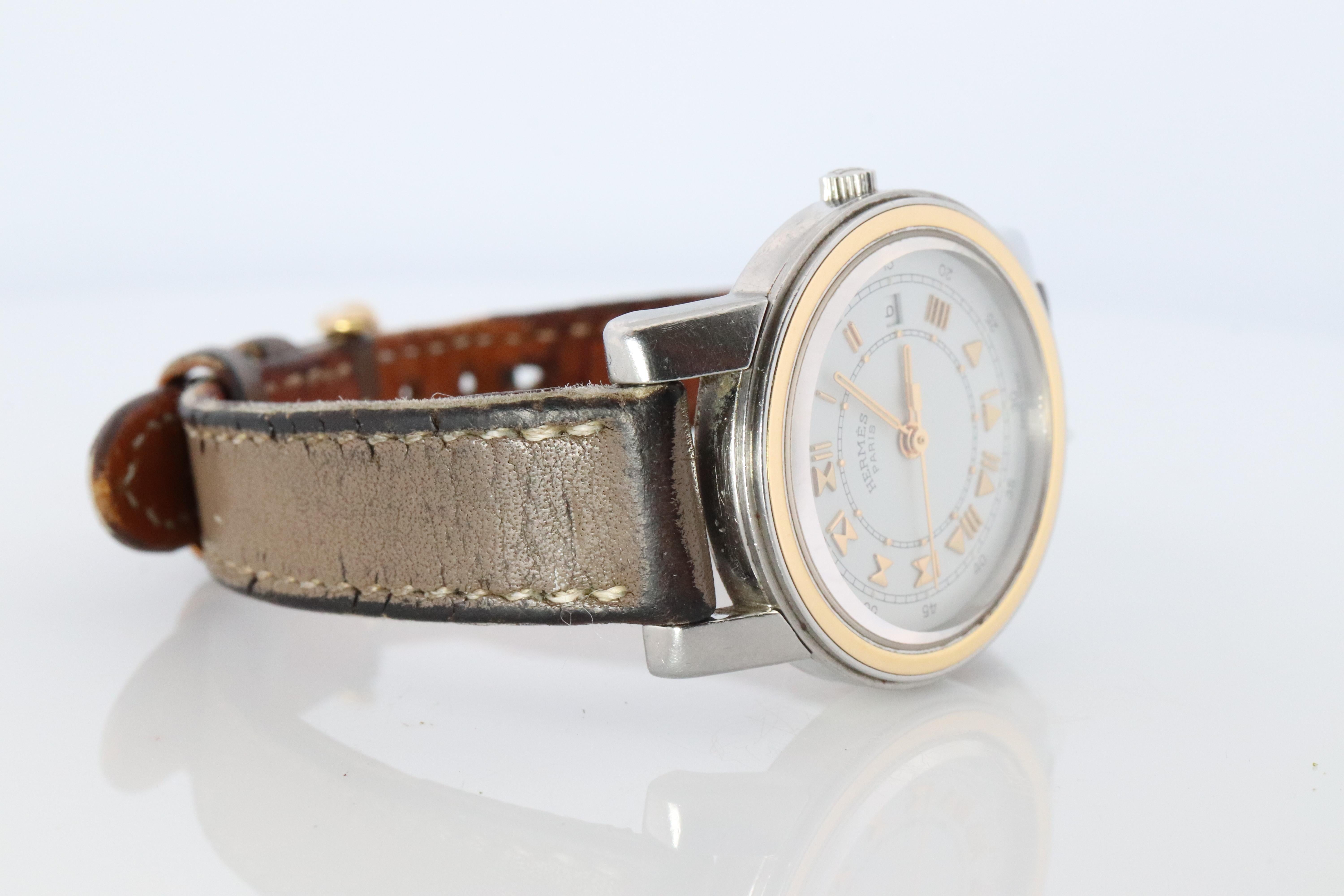 Ce modèle est une authentique HERMES Carrick 26mm Round Case.

26mm RoundCase
ref. CA1.220

Mouvement à quartz.


La montre est fabriquée en acier inoxydable et plaquée 18 carats. Elle présente un cadran blanc, des aiguilles et des index en or, un