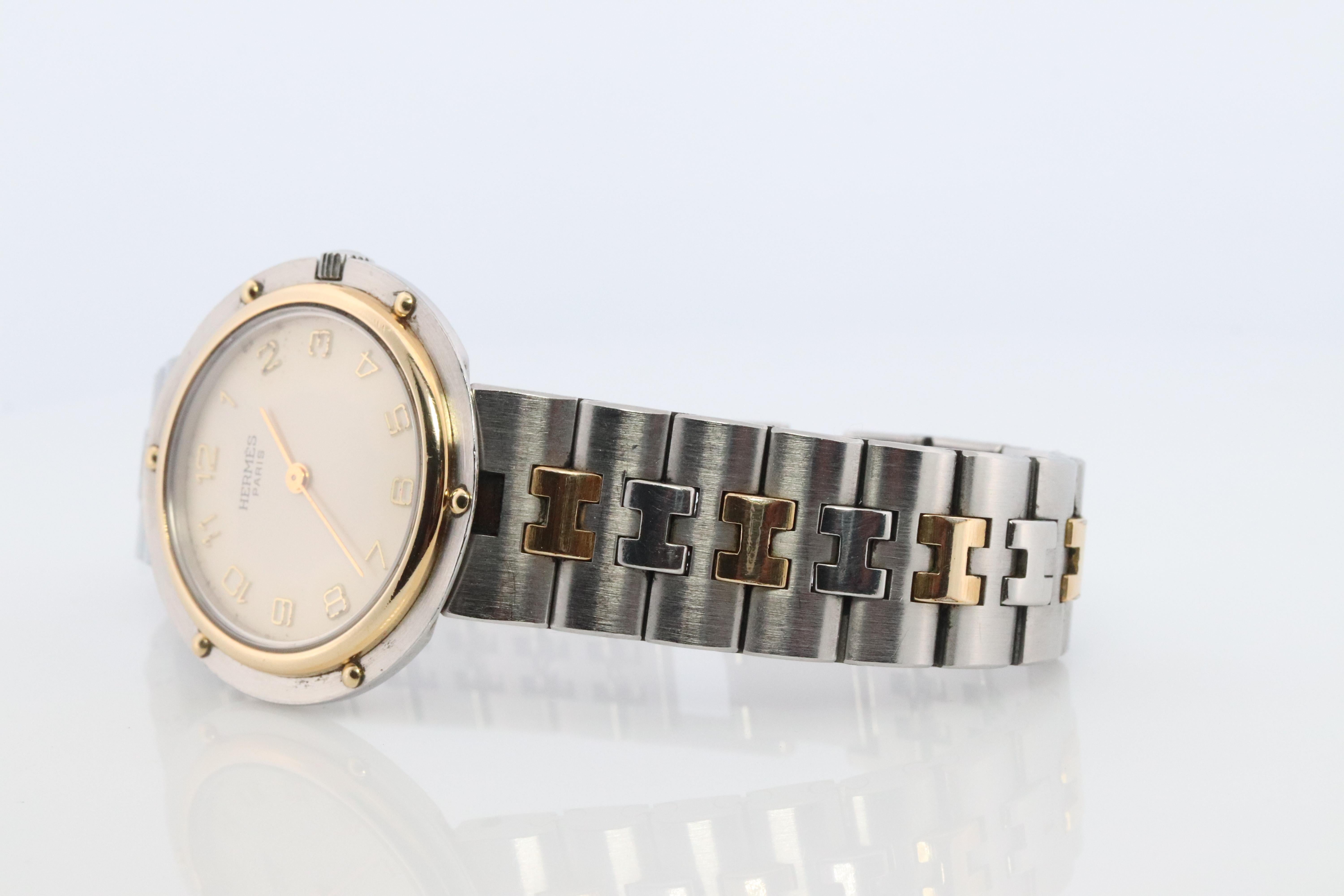This is an authentic HERMES Stainless Steel 

Olympia 30mm Round Case.

Quartz Movement.

UNISEX


The watch is crafted of stainless steel and 18k plated features a white dial, gold hands and hour markers, two tone link bracelet, sapphire crystal,