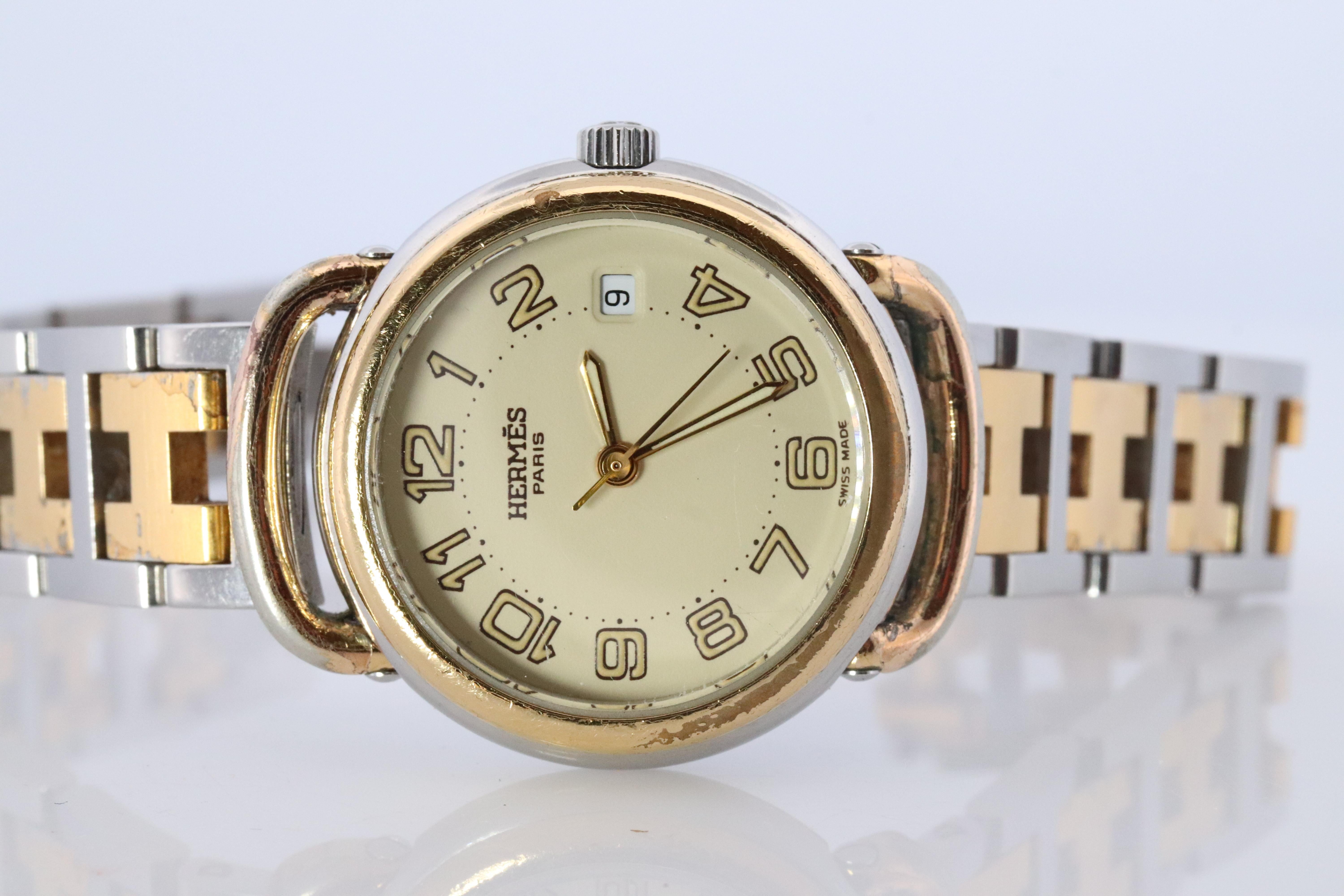 This is an authentic HERMES Stainless Steel 24mm Round Pullman Clipper Quartz round Dial. The watch is crafted of stainless steel and features a champagne dial, gold hands and hour markers, two tone link bracelet, sapphire crystal, and a quartz